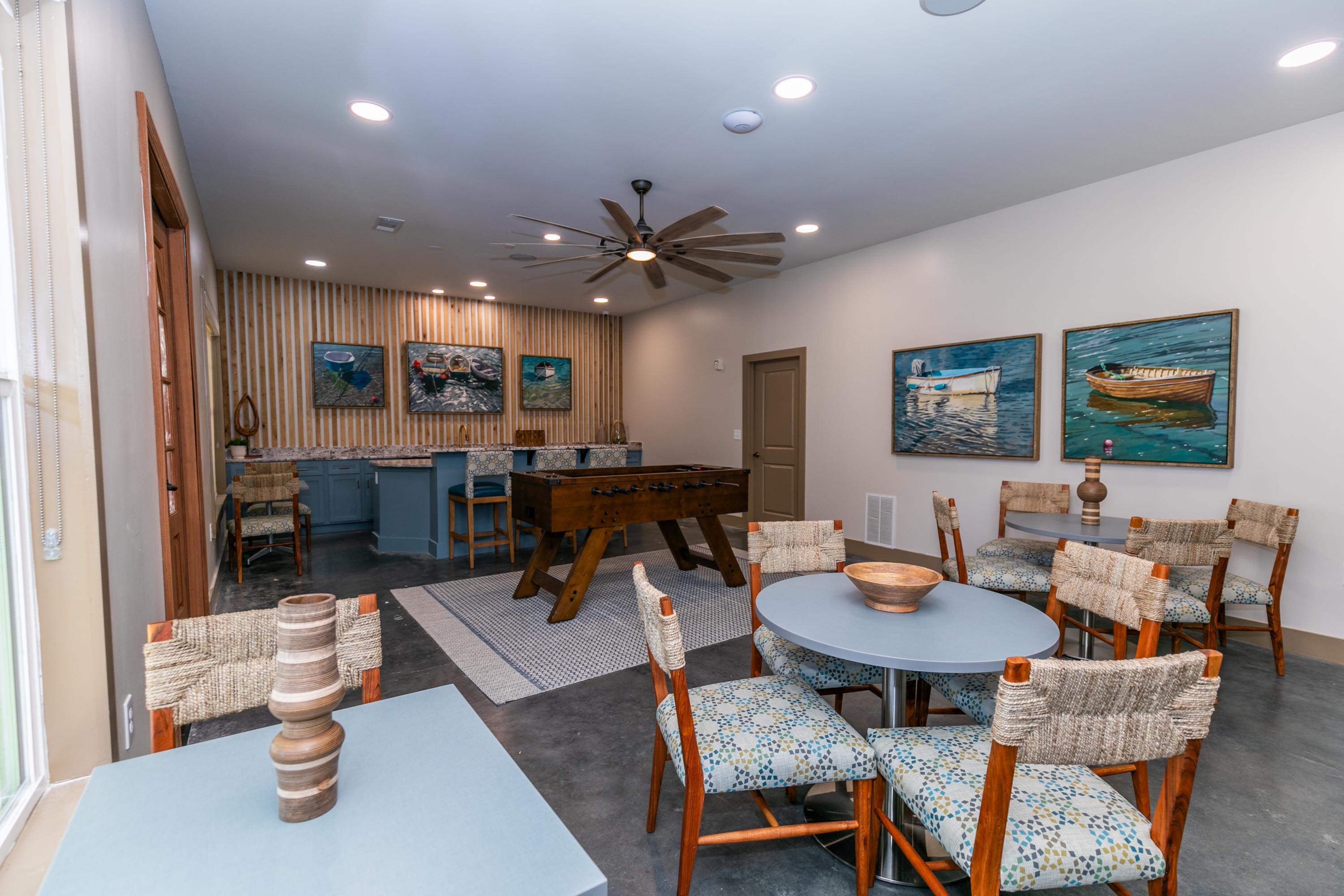 A living room with a pool table, inviting chairs, and a ceiling fan at Thomaston Crossing in Macon, Georgia