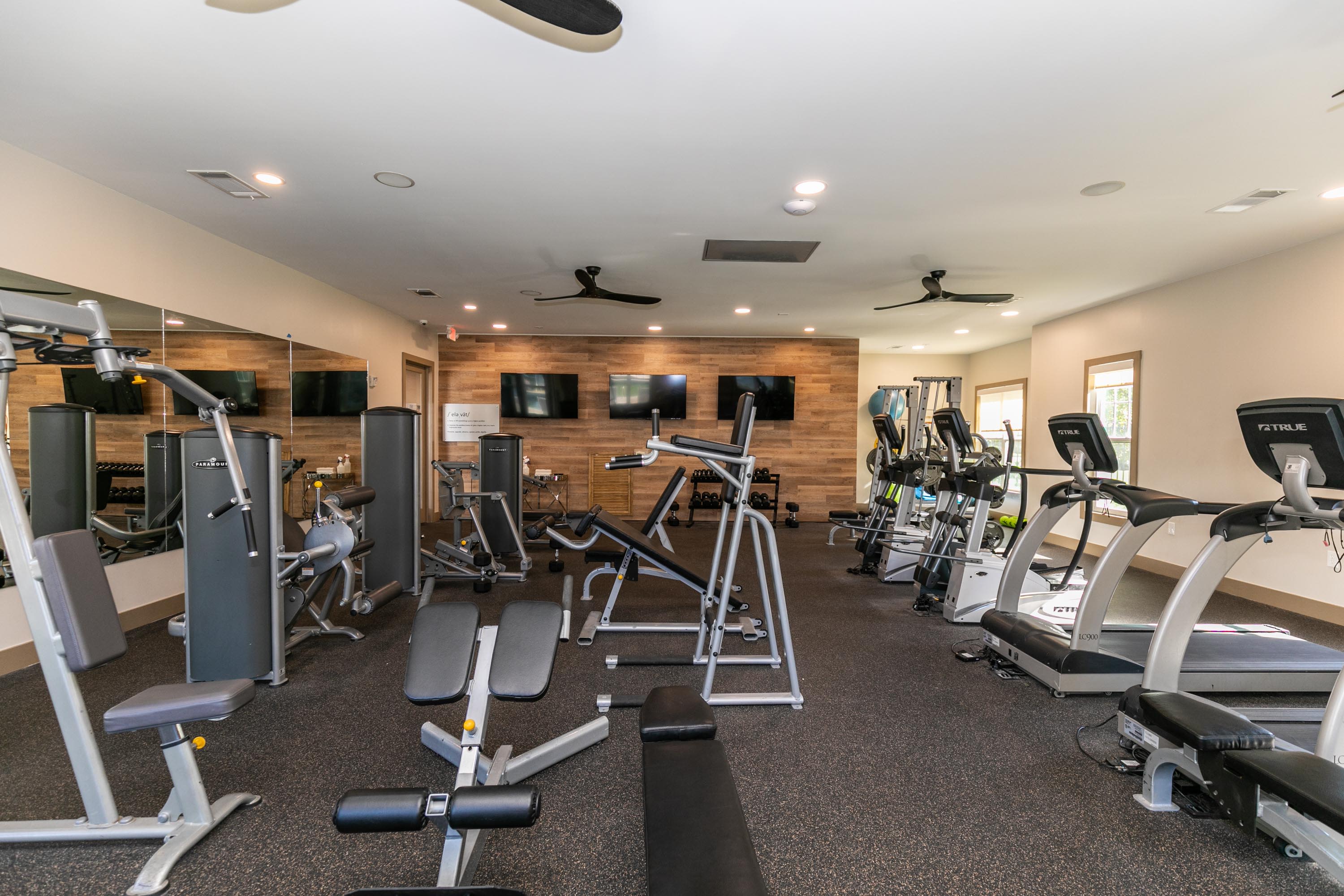 A gym room with exercise machines and mirrors at Thomaston Crossing in Macon, Georgia