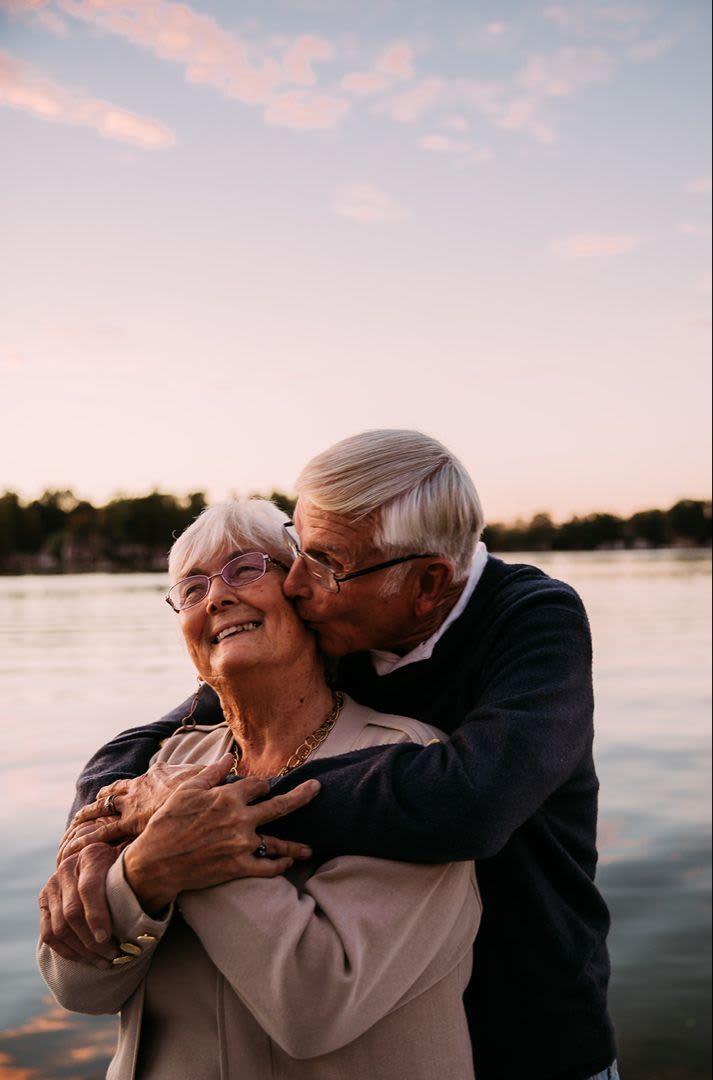 A senior couple shares a tender kiss by the lake at Brightwater Senior Living in Bend, Oregon.