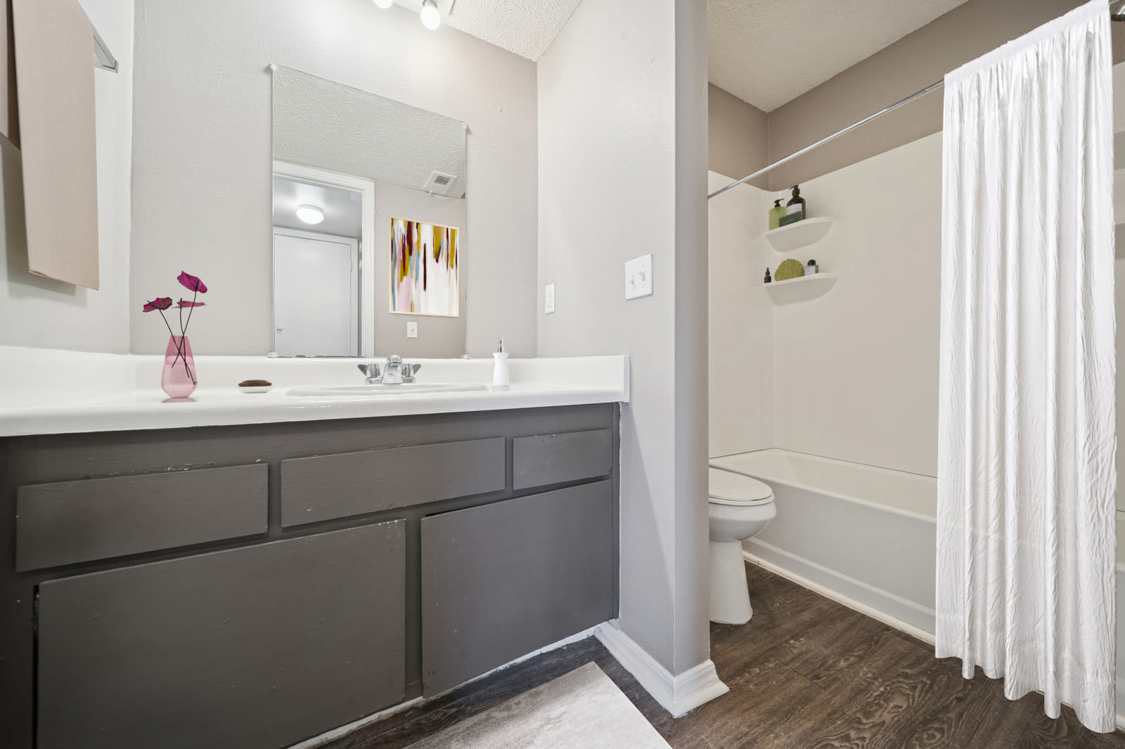 A bathroom with a sink, toilet, and shower, with neutral-colored walls and tiled flooring at Reeds Landing Apartments in Edmond, Oklahoma