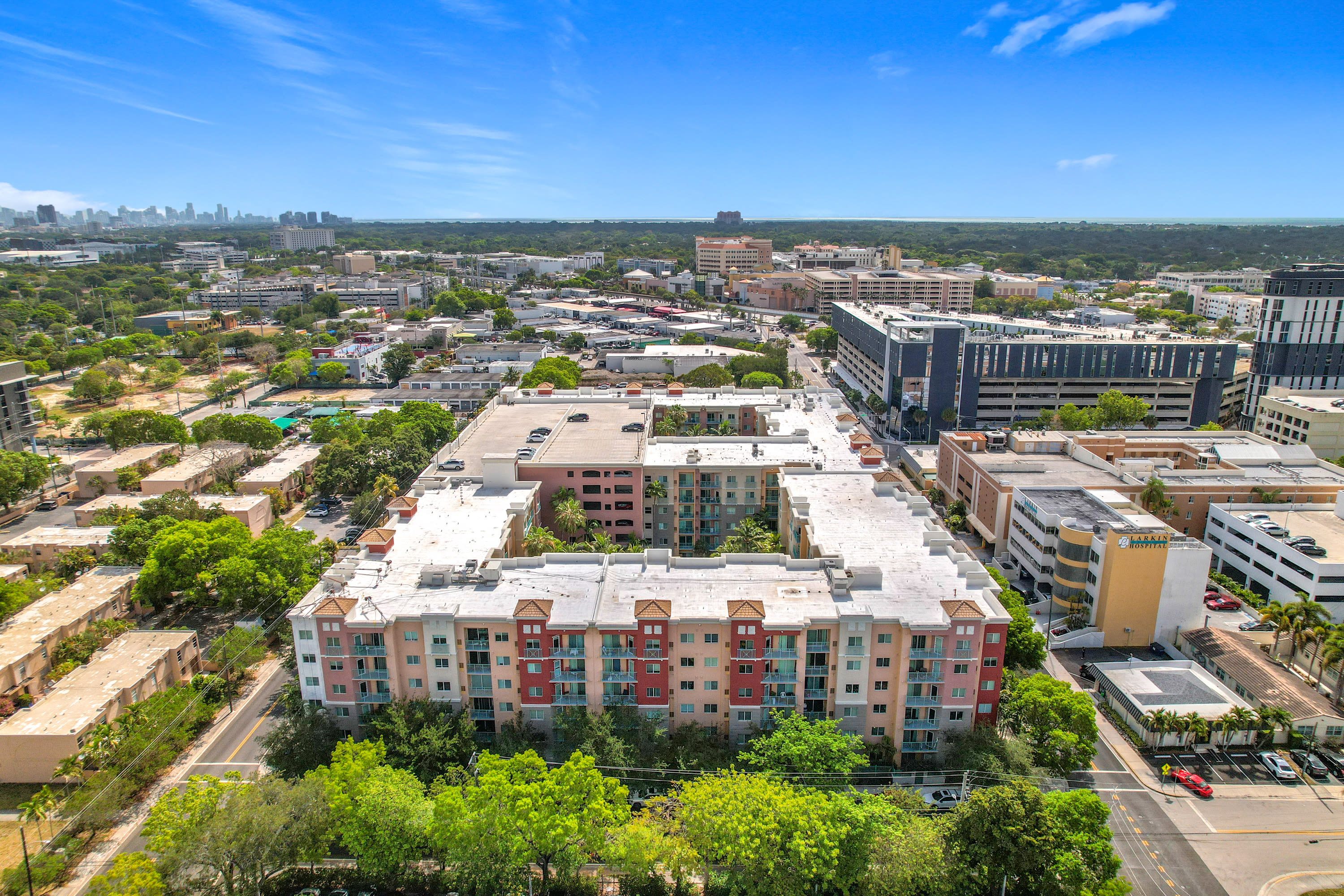 Aerial view of a multi-story apartment complex surrounded by other buildings and greener yat Valencia South Miami in South Miami, Florida