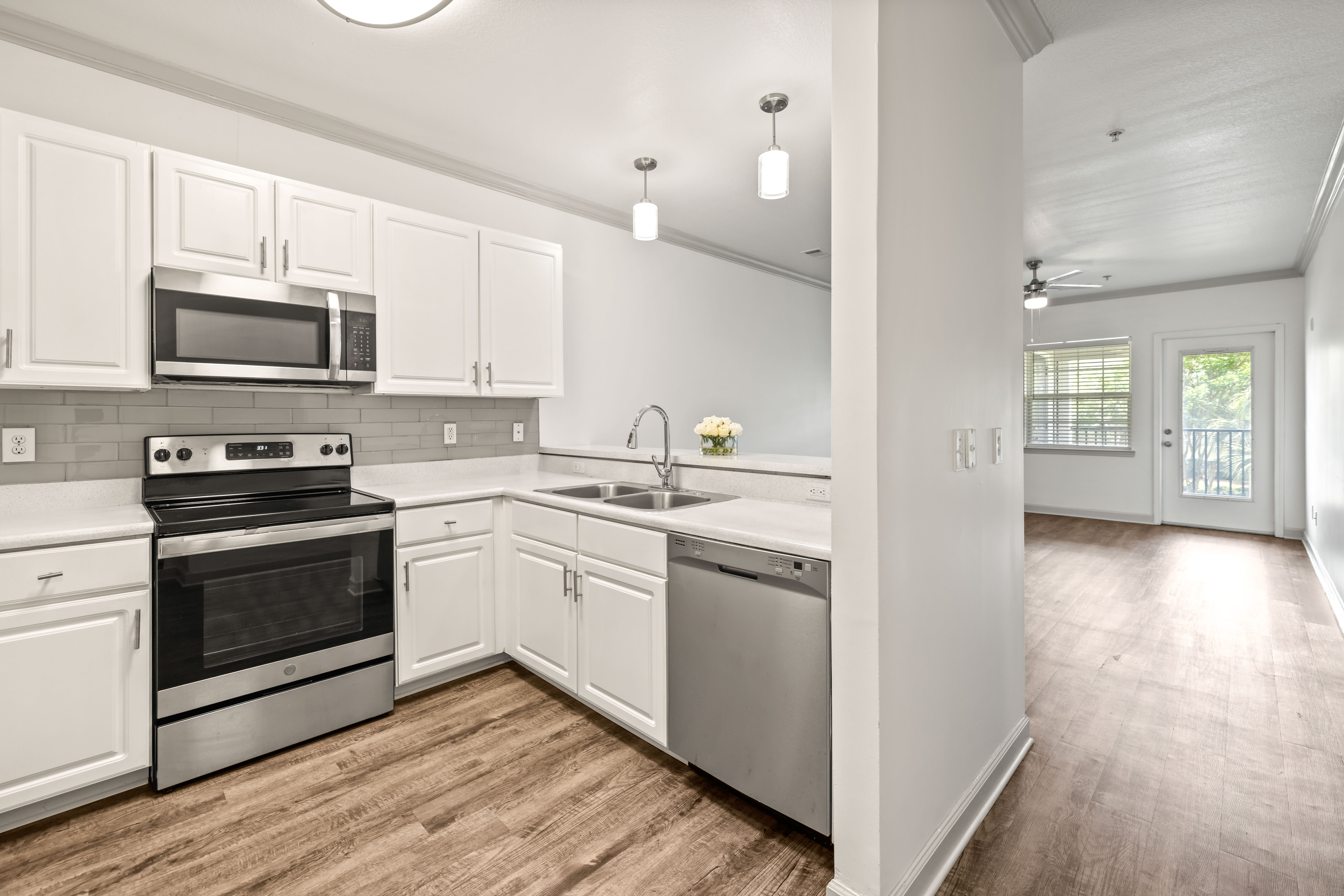 View of the living area over the kitchen's breakfast bar in a model apartment at Olympus Carrington in Pooler, Georgia