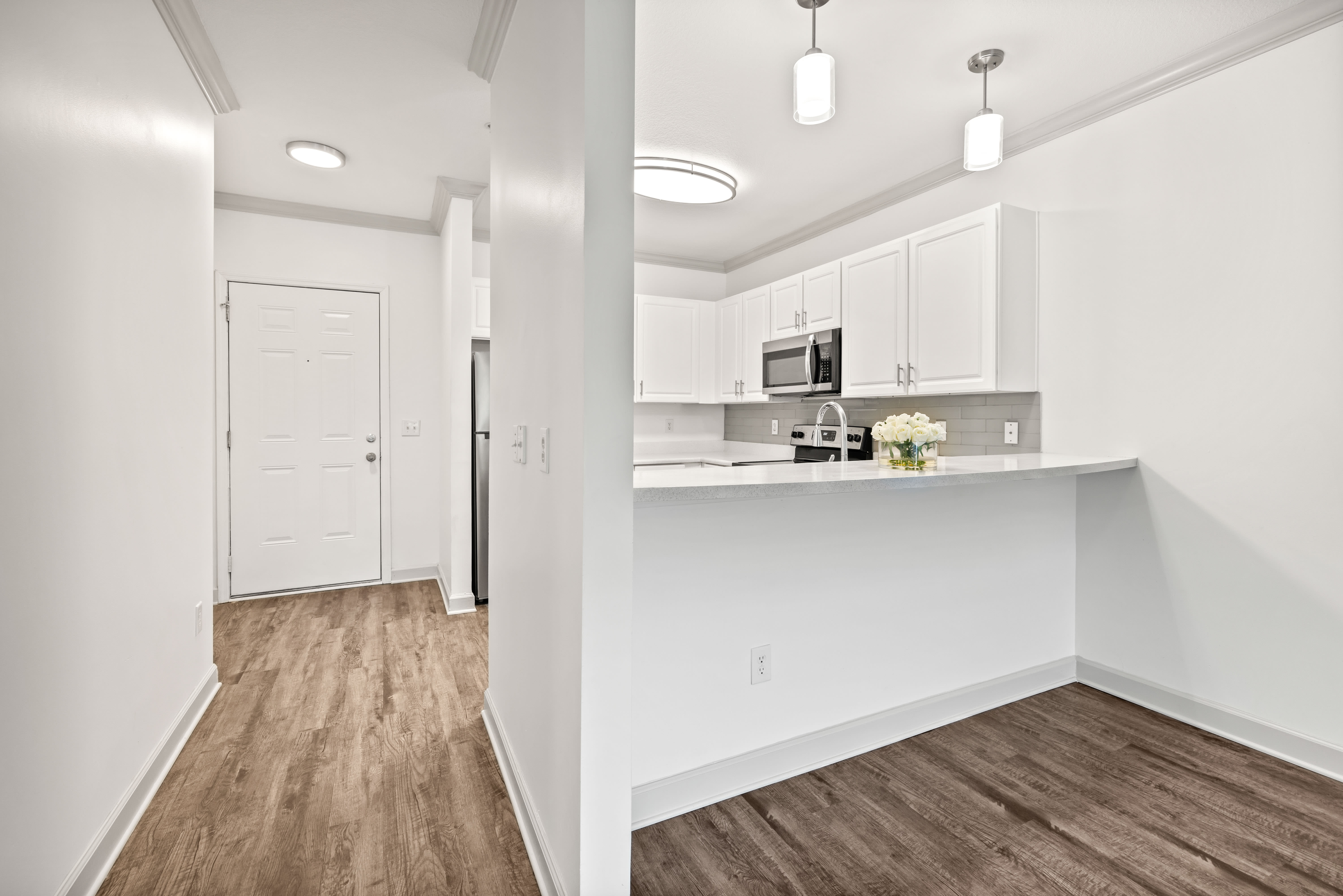 View of the living area over the kitchen's breakfast bar in a model apartment at Olympus Carrington in Pooler, Georgia