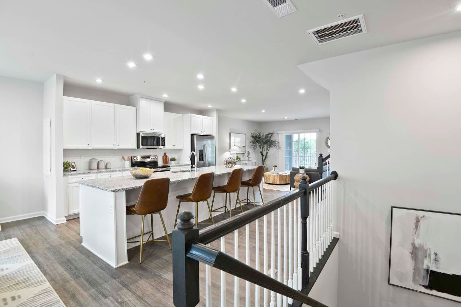 Contemporary kitchen with a large island, bar stools, white cabinetry, and a view of the living area, creating a spacious and modern atmosphere at Dorsey Overlook in Ellicott City, Maryland