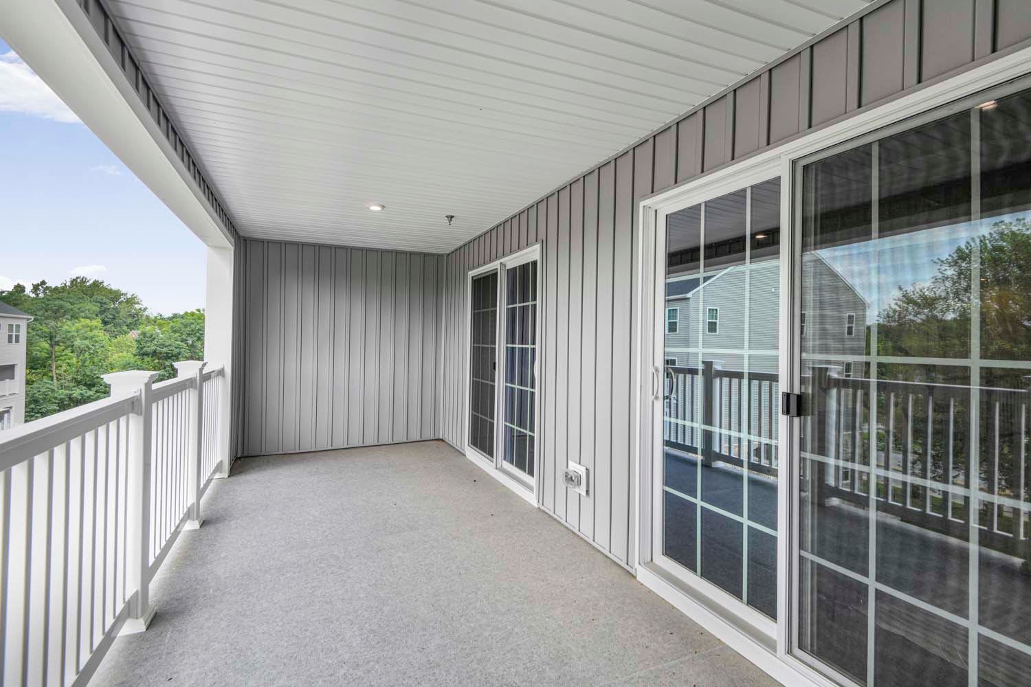 Spacious balcony with grey paneling and sliding glass doors, featuring a clean, open space and a view outside at Dorsey Overlook in Ellicott City, Maryland