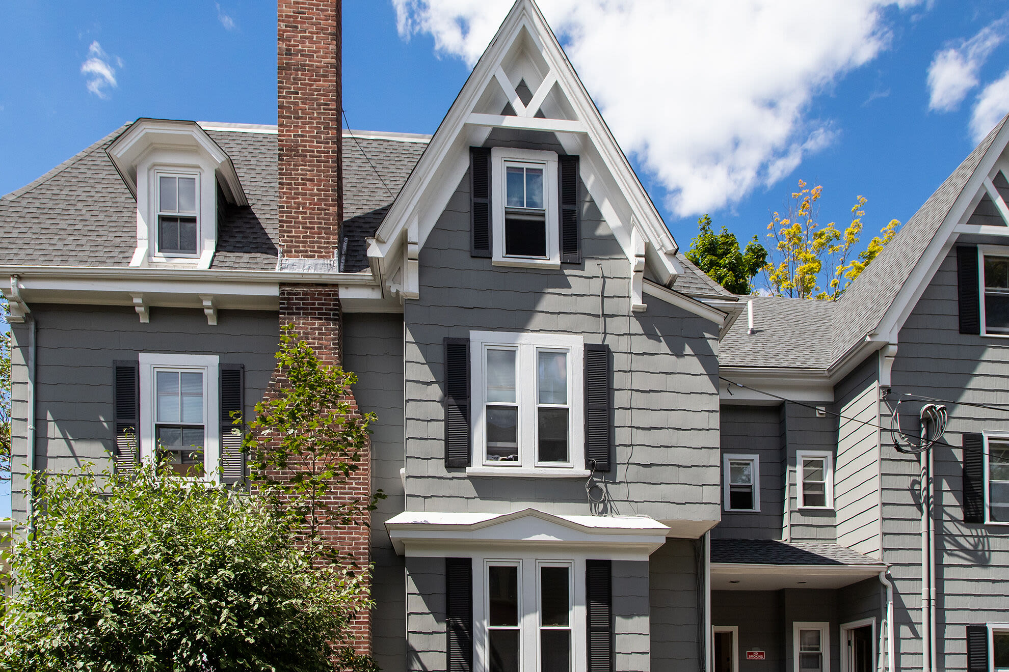 Angled view of a residential building with brick exterior, bay windows, and surrounding greenery at Hearth at Burroughs in Jamaica Plain, Massachusetts