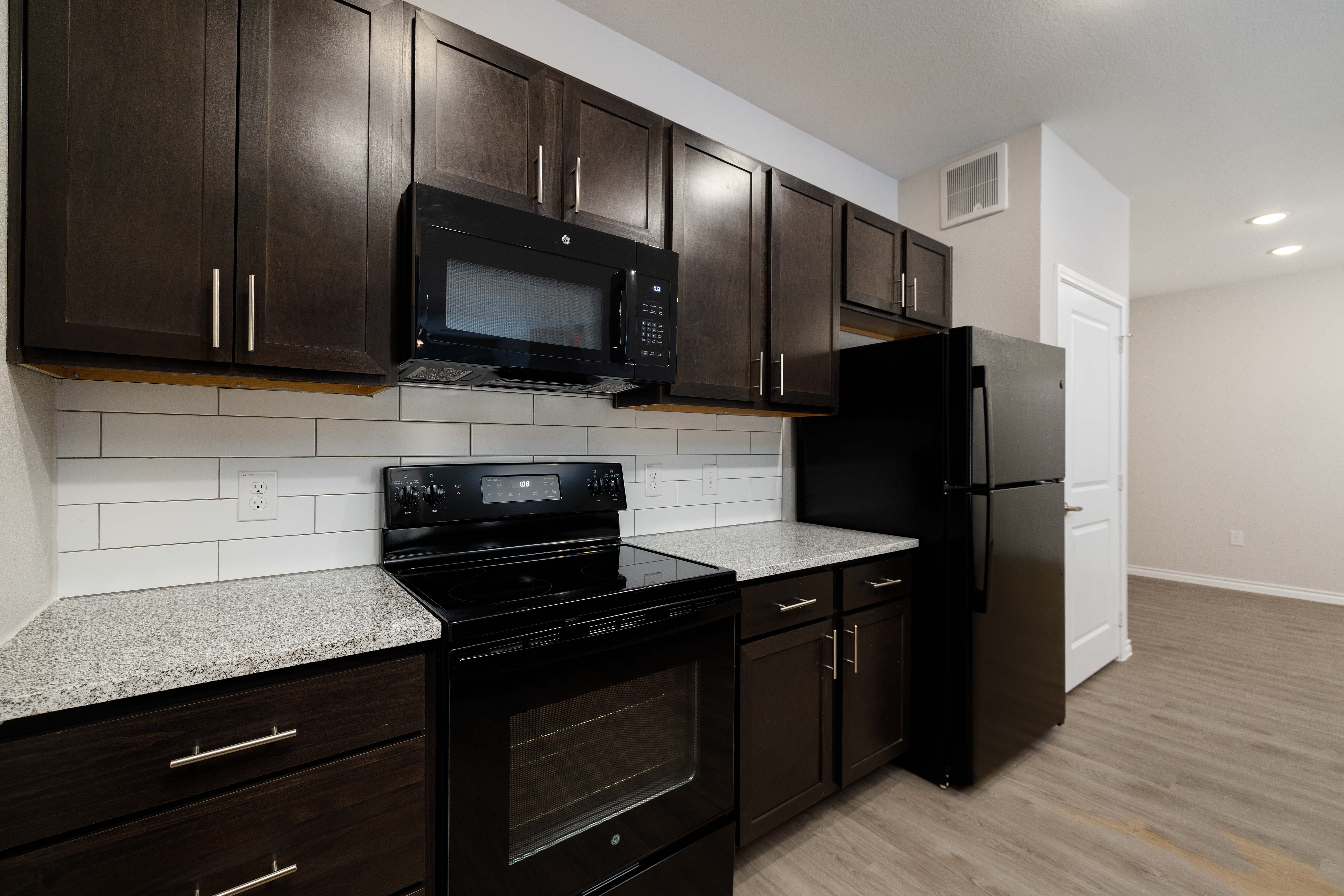 Kitchen with black appliances in a modern apartment home at The Janson in Del Valle, Texas