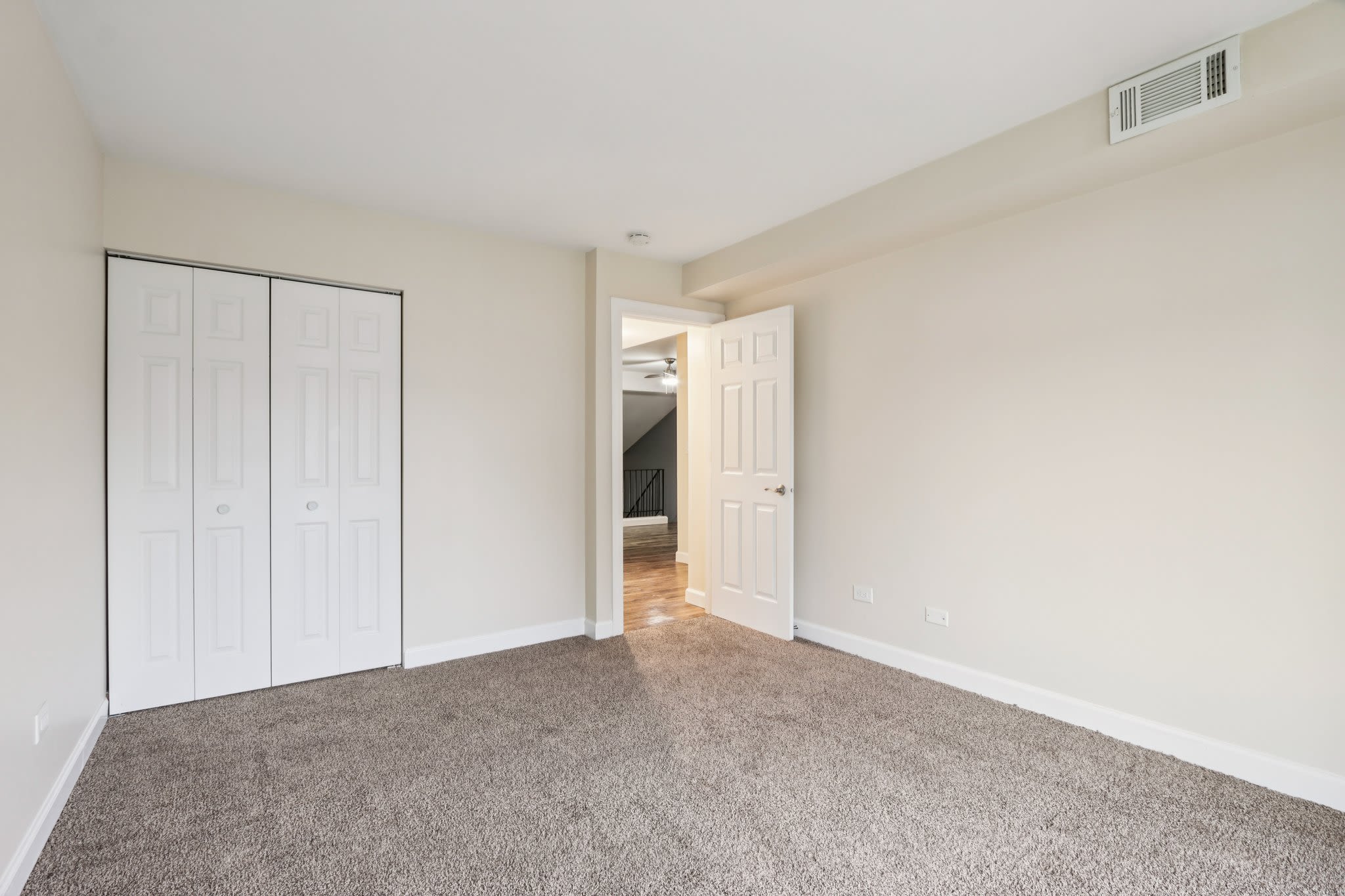 An unfurnished bedroom showing carpeted flooring and connection to other rooms at Crystal Lake Apartments in Crystal Lake, Illinois