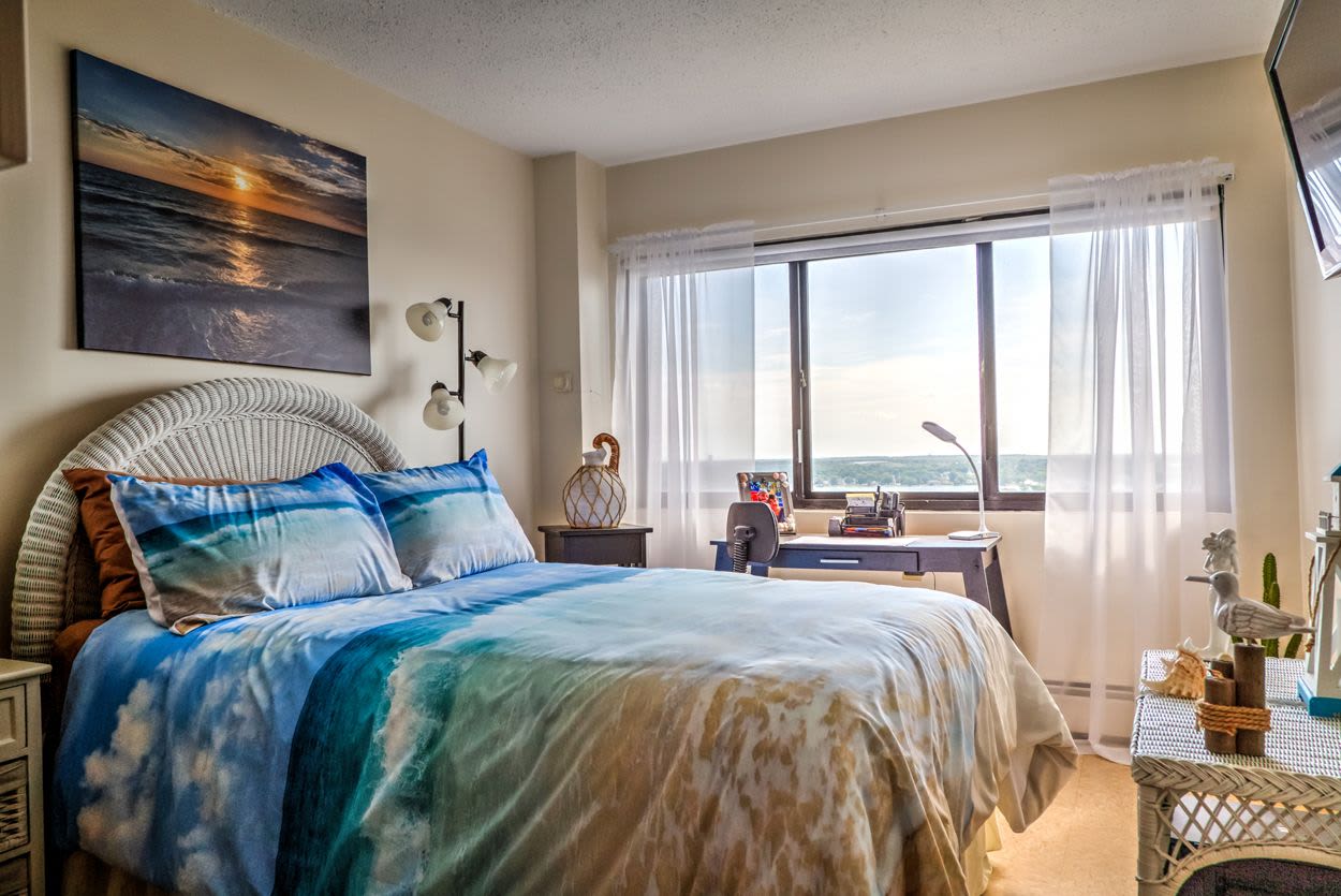 Well-lit bedroom with cozy bed at Melville Towers in New Bedford, Massachusetts