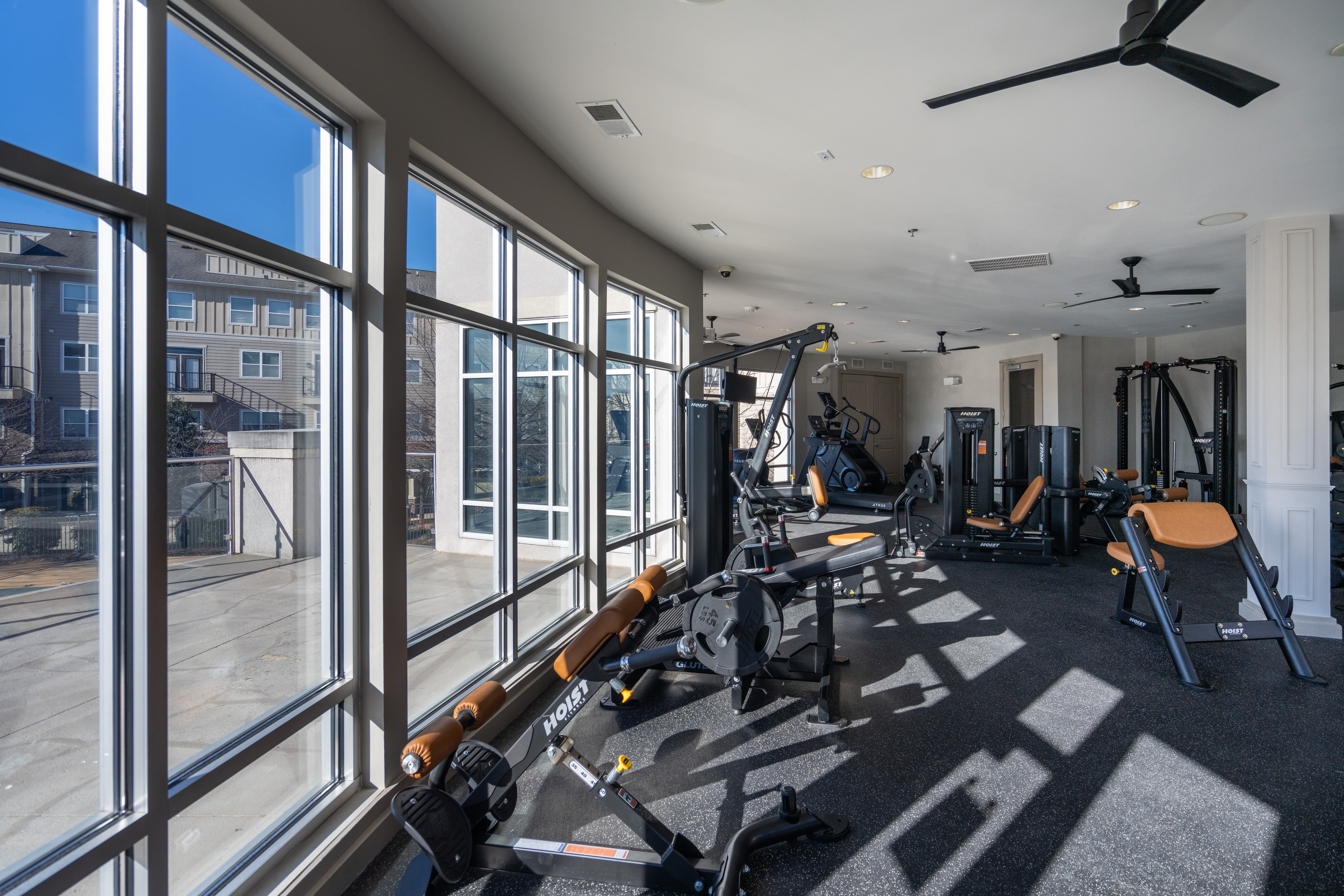 Small fitness room with two stationary bikes, a rack of dumbbells, kettlebells, and large exercise balls beside a window at The James in Richmond, Virginia