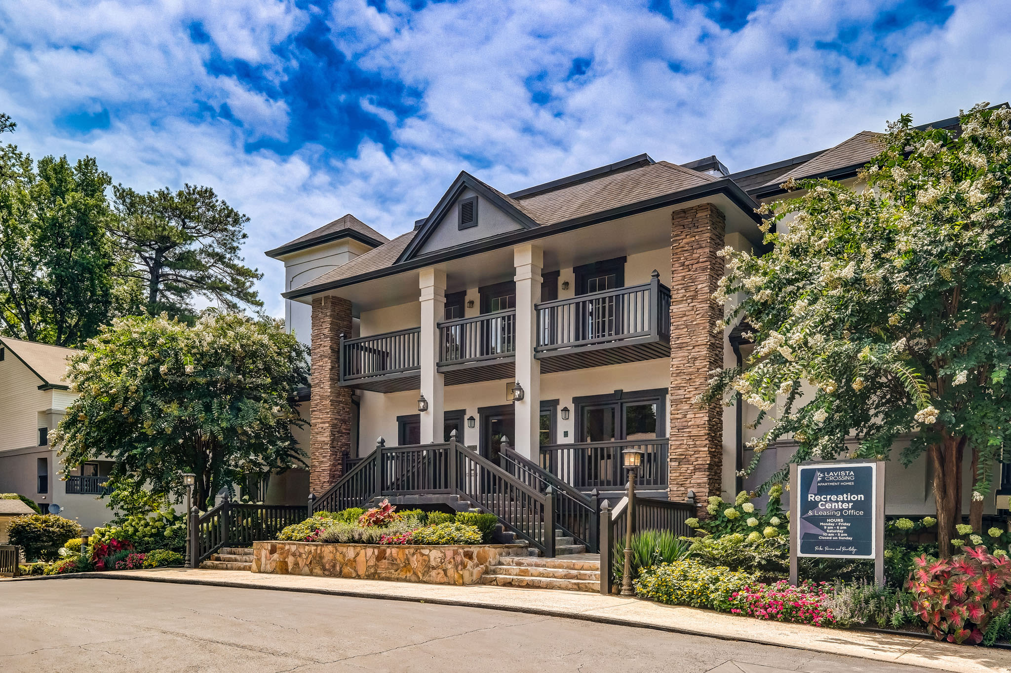 Leasing office or clubhouse exterior with stone columns, balconies, and landscaped entrance at LaVista Crossing in Tucker, Georgia