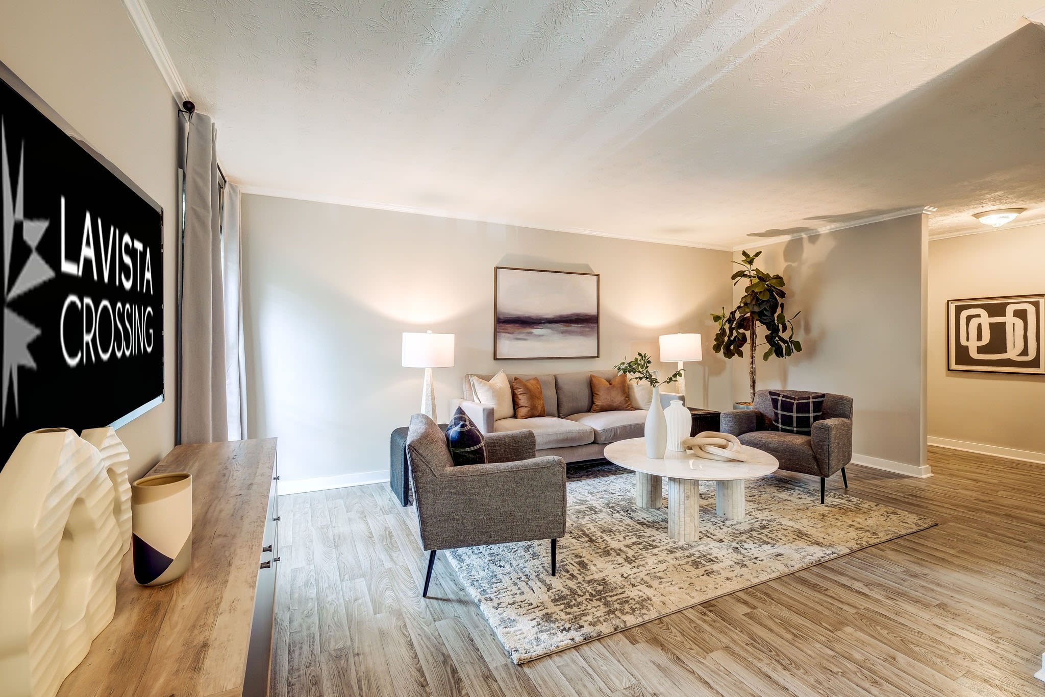 Spacious living room with modern décor, accent chairs, large rug, and TV console at LaVista Crossing in Tucker, Georgia