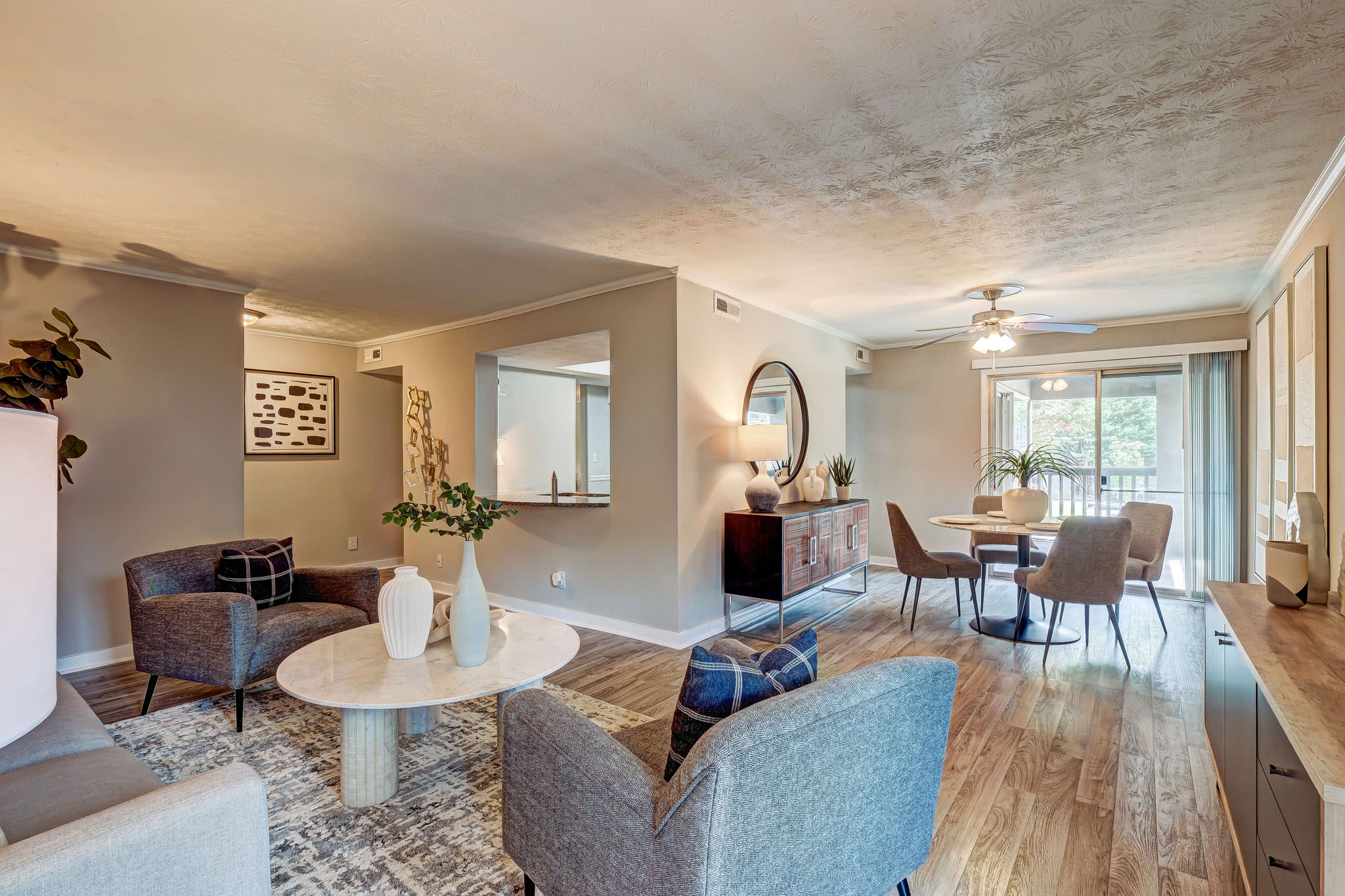 Open-concept living and dining area with modern furnishings, large windows, and hardwood-style flooring at LaVista Crossing in Tucker, Georgia