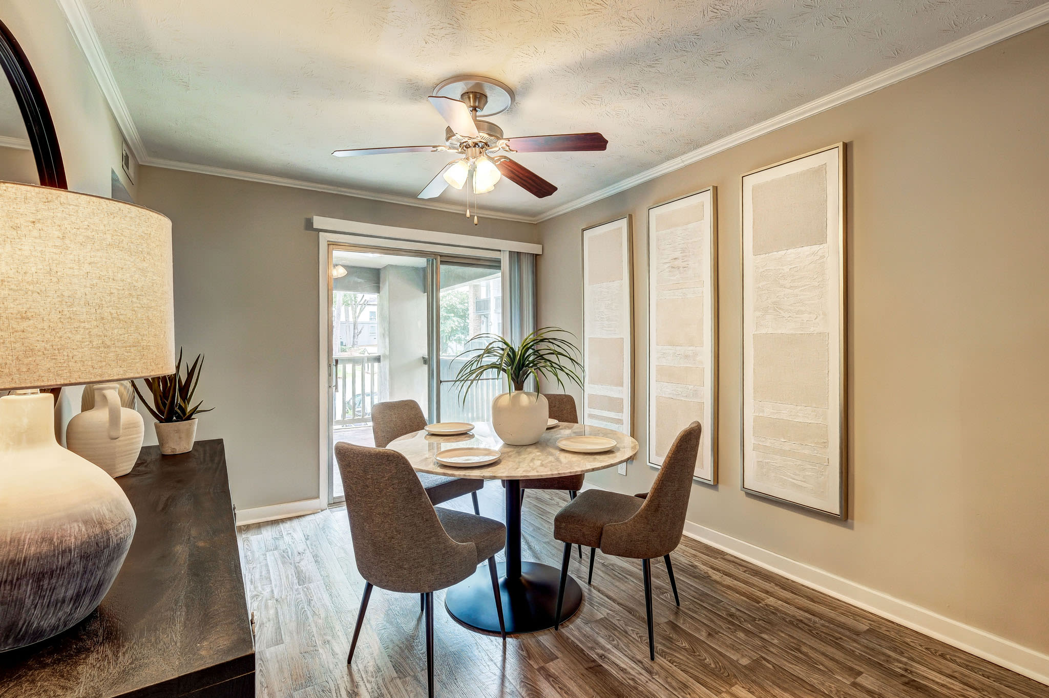 Dining room with round table, upholstered chairs, ceiling fan, and sliding glass doors at LaVista Crossing in Tucker, Georgia