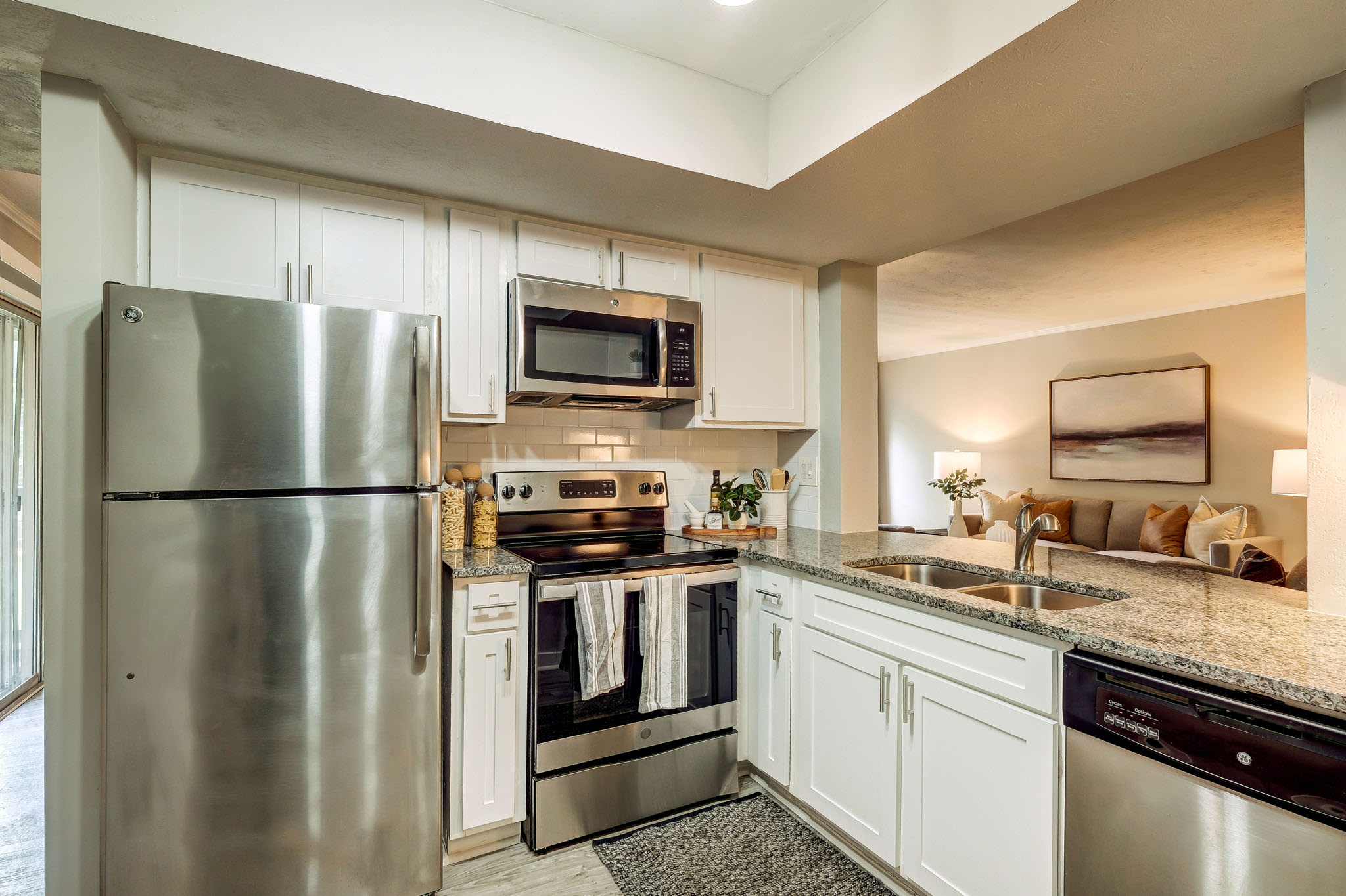 Kitchen view from countertop with stainless appliances, granite counters, and adjacent laundry area at LaVista Crossing in Tucker, Georgia