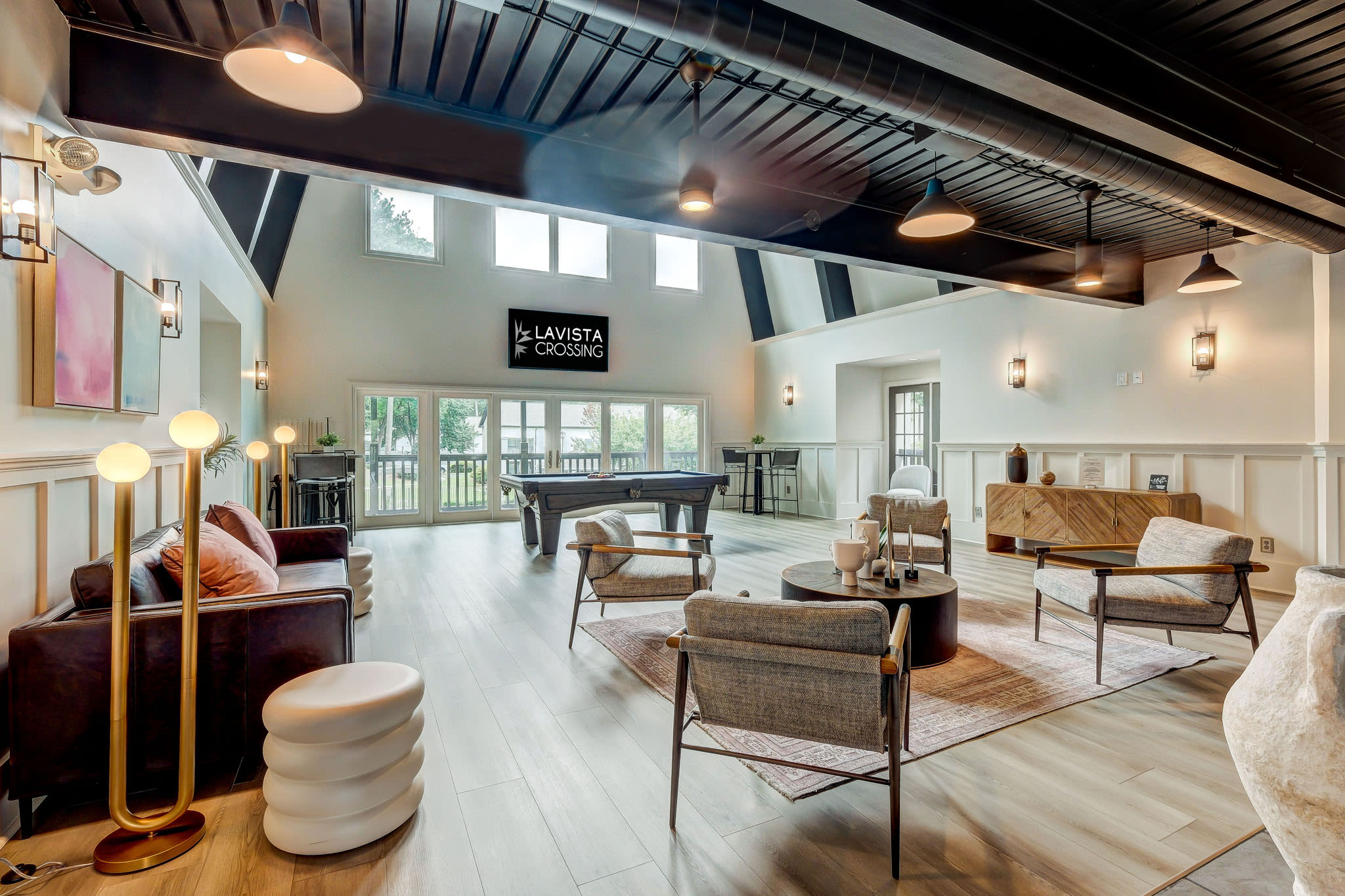 Clubhouse lounge with stylish seating, pool table, and tall windows providing natural light at LaVista Crossing in Tucker, Georgia