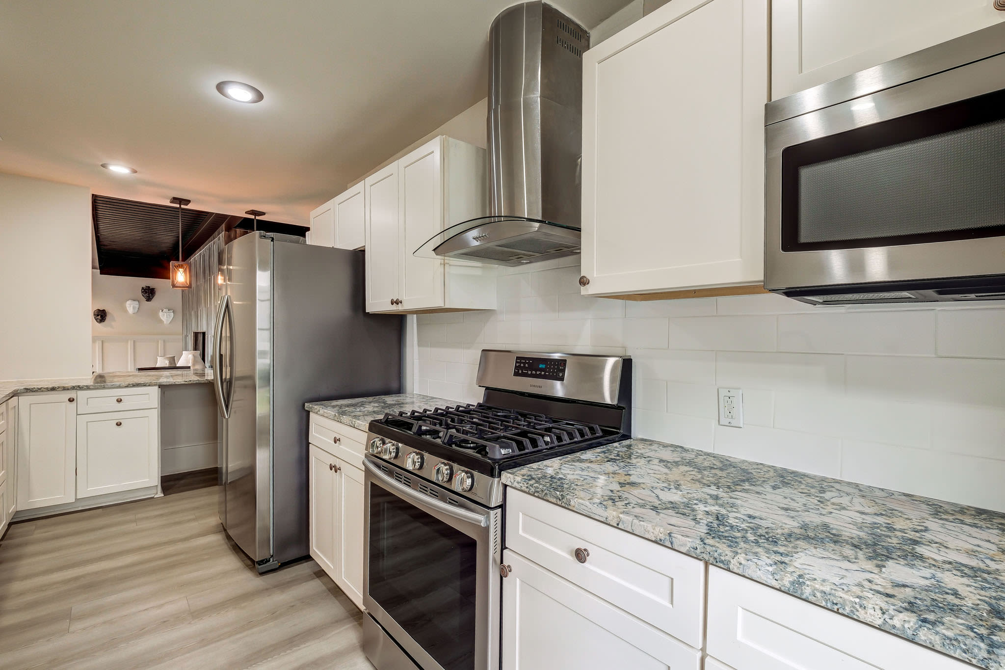 Kitchen view from countertop with stainless appliances, granite counters, and adjacent laundry area at LaVista Crossing in Tucker, Georgia