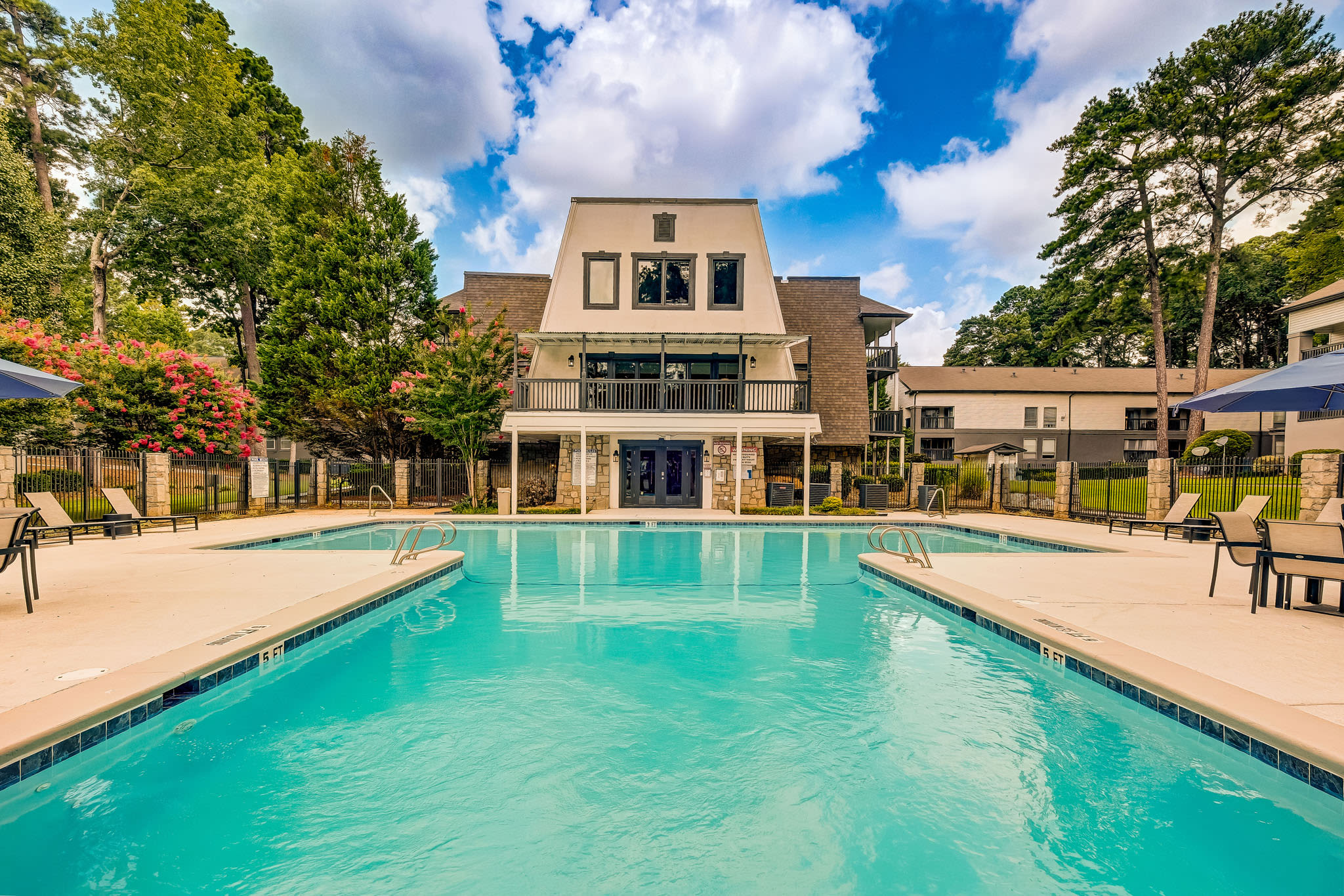 Resort‑style swimming pool with lounge chairs, umbrellas, and clubhouse building in the background at LaVista Crossing in Tucker, Georgia