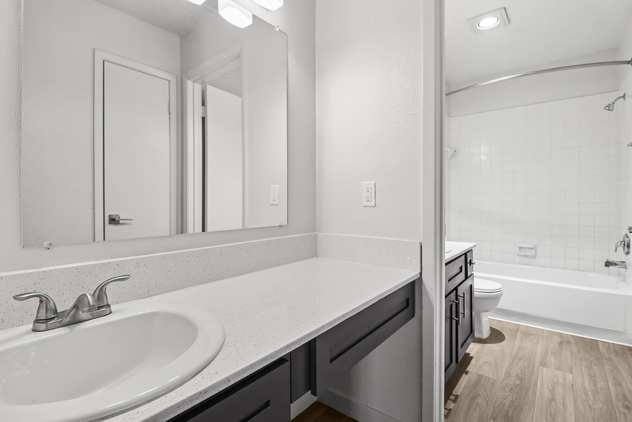Bathroom with long vanity, single sink, and view into a tub and shower area at Pinewood Estates in Albuquerque, New Mexico