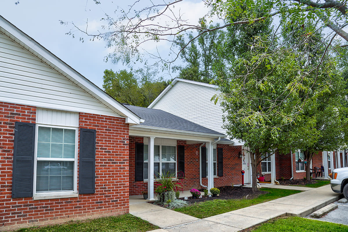 Brick exterior apartment with landscaped entrance and sidewalk, featuring large windows and porch area at Paint Landing in Stambaugh, Kentucky