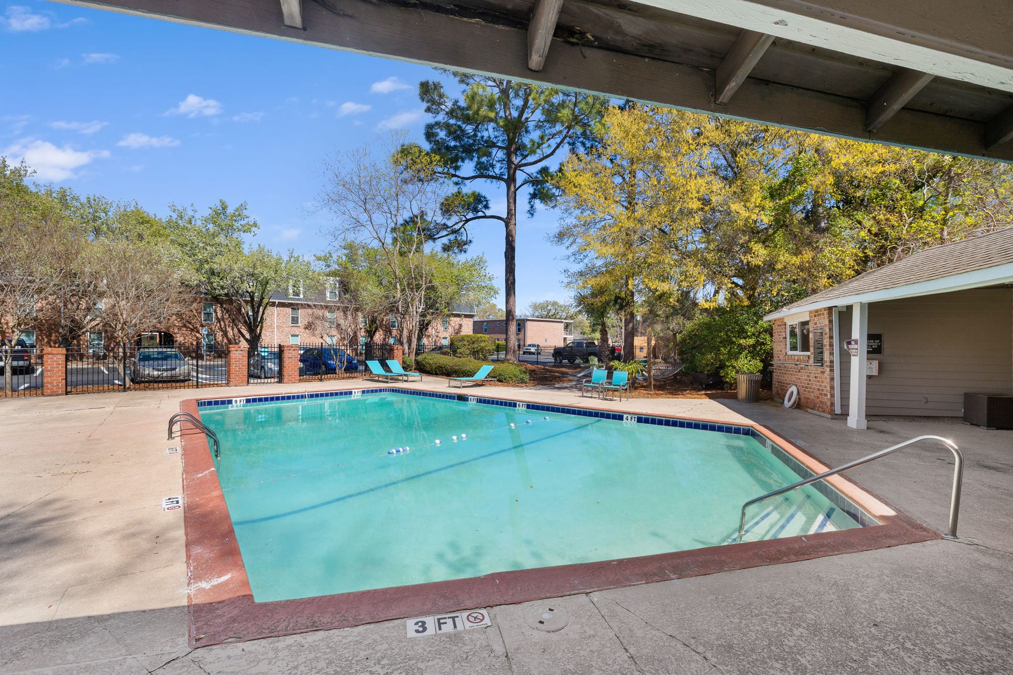 Swimming pool with handrails, surrounding deck, and apartment buildings beyond fencing at Palmetto Square in Charleston, South Carolina
