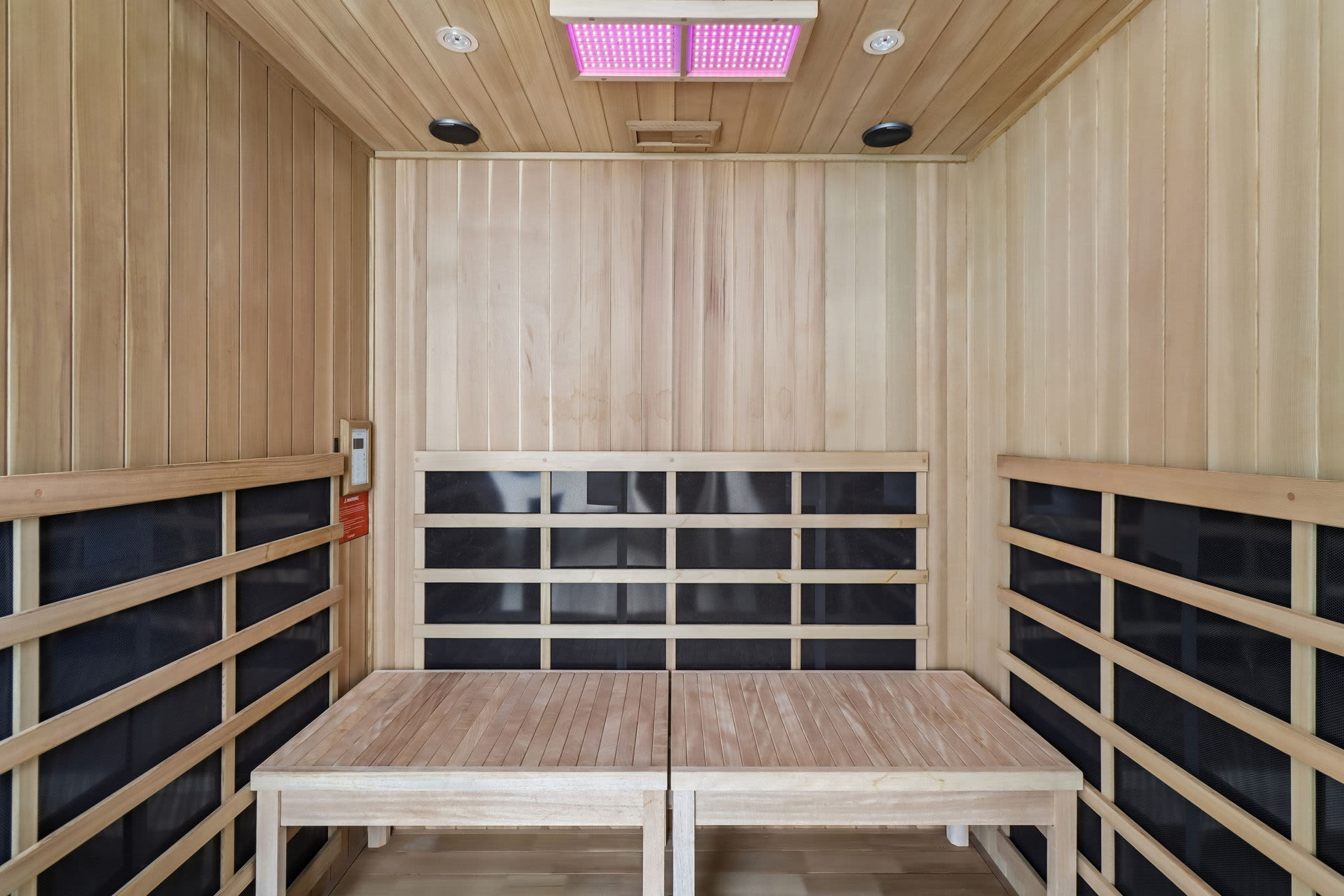 Private infrared sauna room with wood paneling, bench seating, and ceiling light panels at Treehouse in San Diego, California.