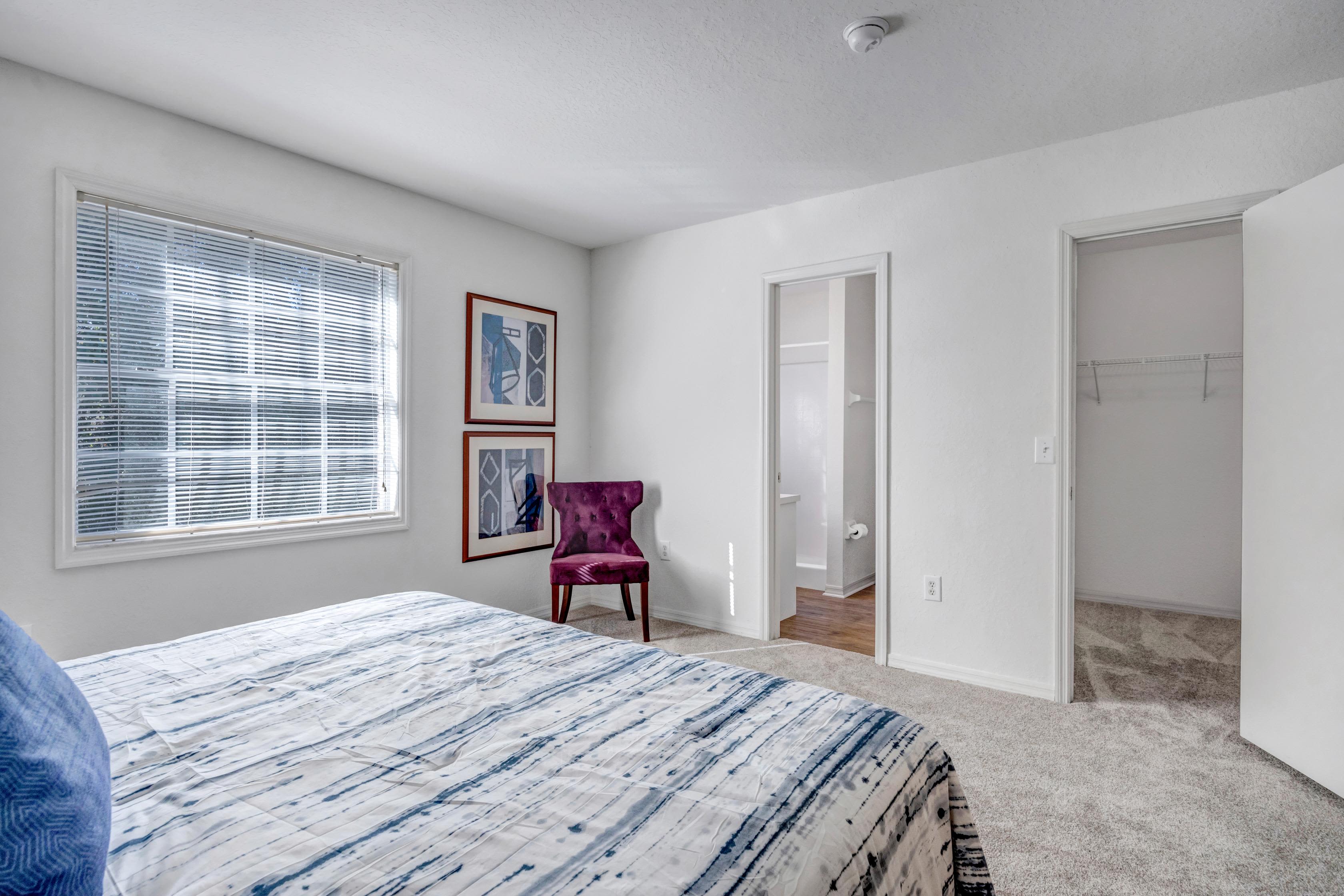 Spacious Modern bedroom with bed and corner chair at Carlton Arms Of Ocala in Ocala, Florida
