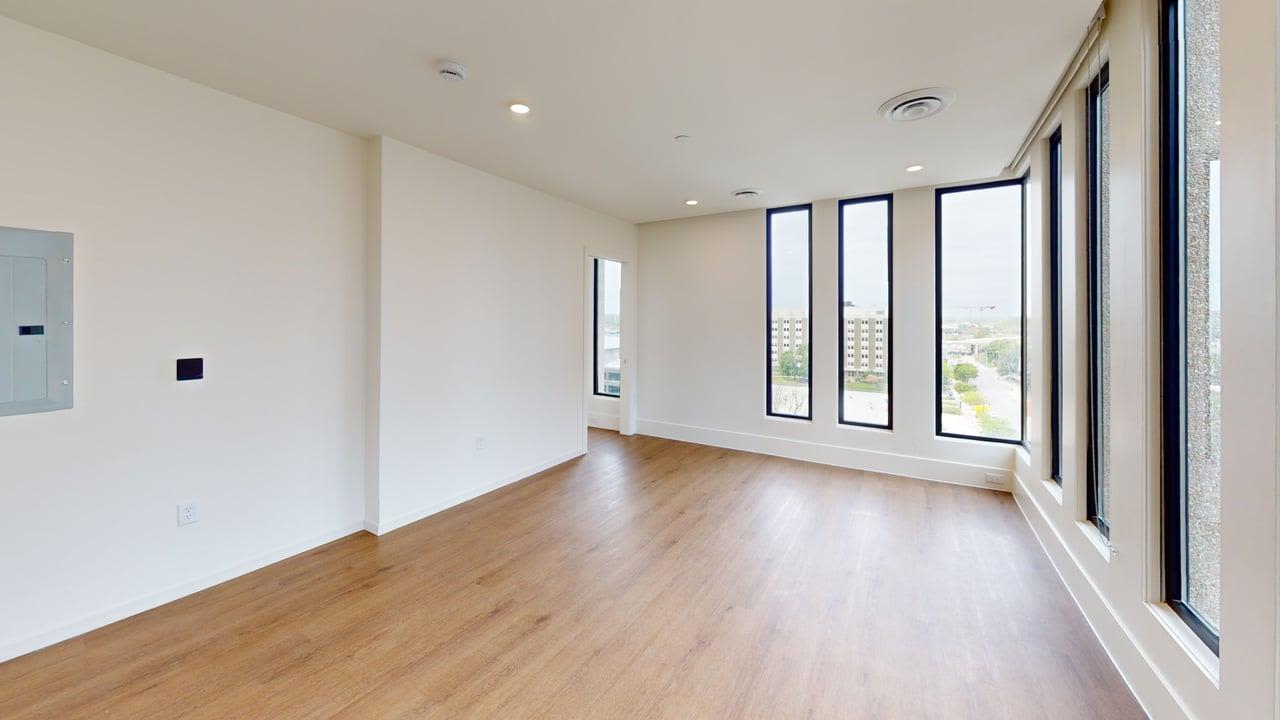 Bright room with large windows and wood-style flooring, showcasing an open layout and modern design at Residences at 111 Lyon in Grand Rapids, Michigan