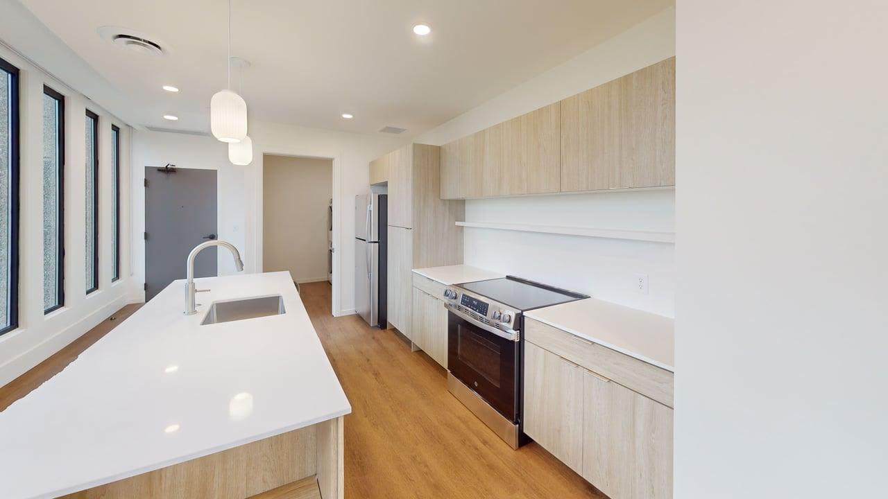 Open layout kitchen with stainless steel appliances, granite countertops, and wood-style flooring at Residences at 111 Lyon in Grand Rapids, Michigan