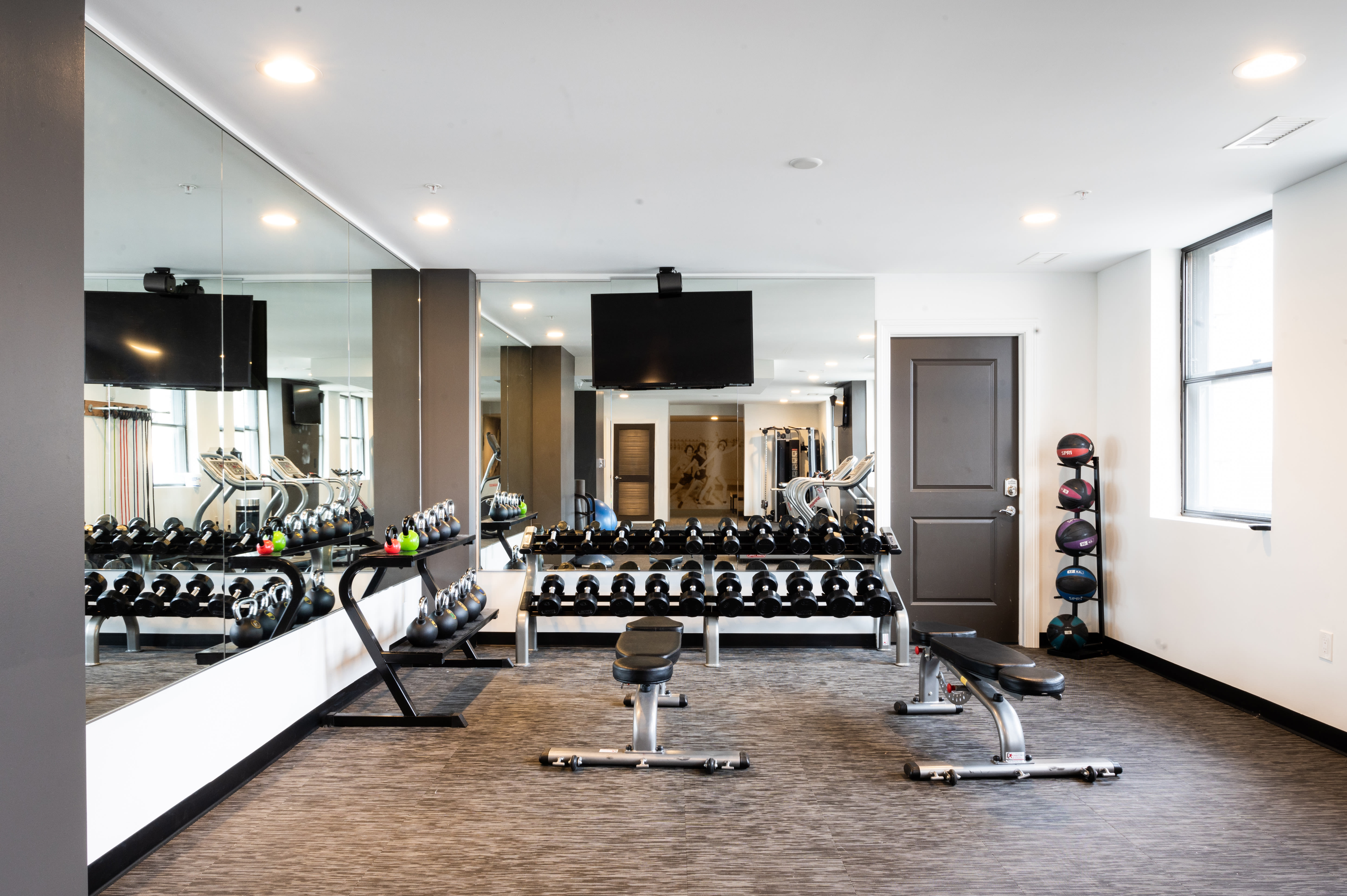 Modern gym with weights, benches, and large mirrors at LeVeque Tower in Columbus, Ohio