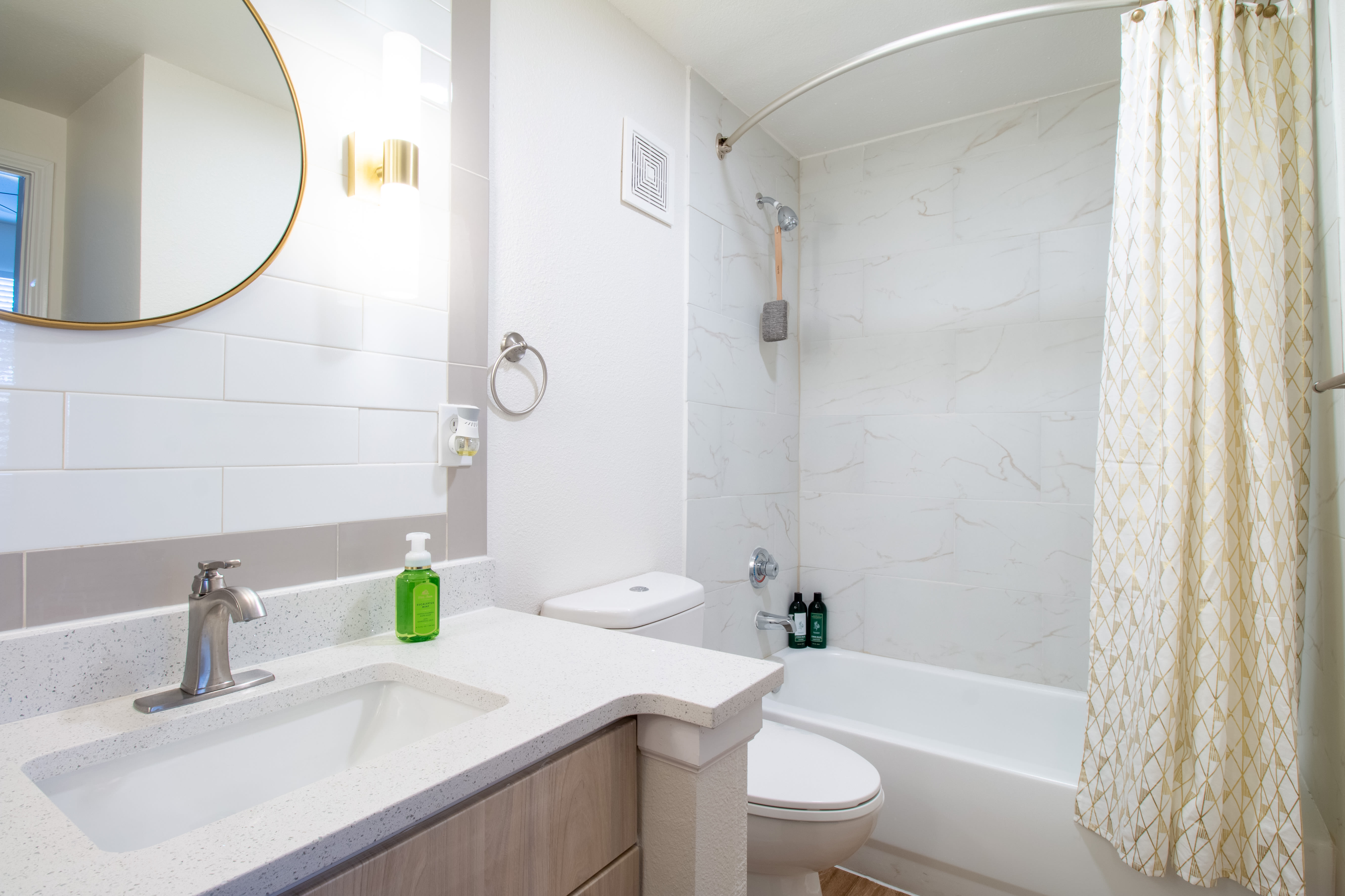 Modern bathroom with a round mirror at Sutton in Austin, Texas