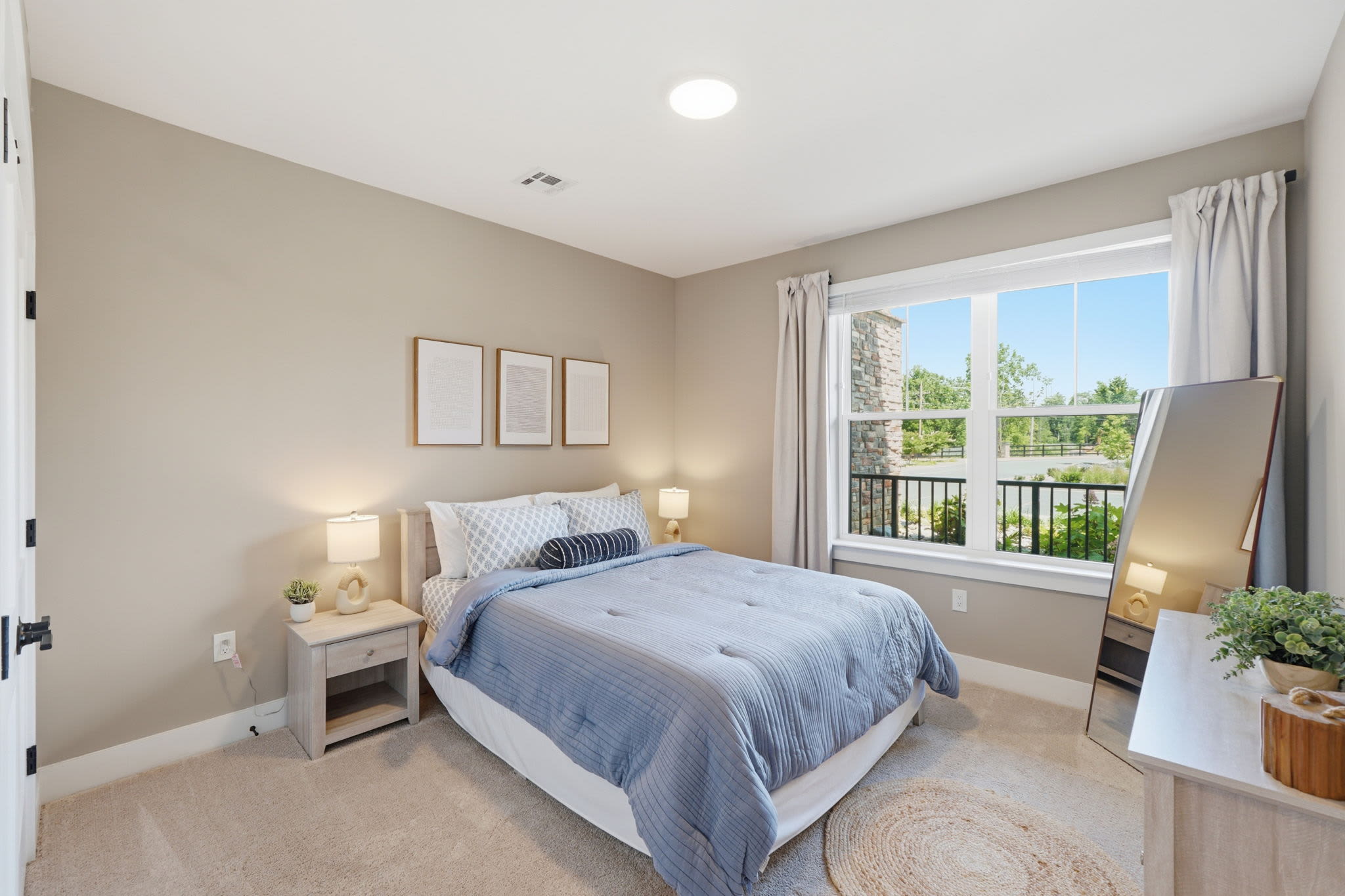 Bright and spacious guest suite bedroom featuring a queen-size bed with blue bedding at Upper East in Frederick, Maryland