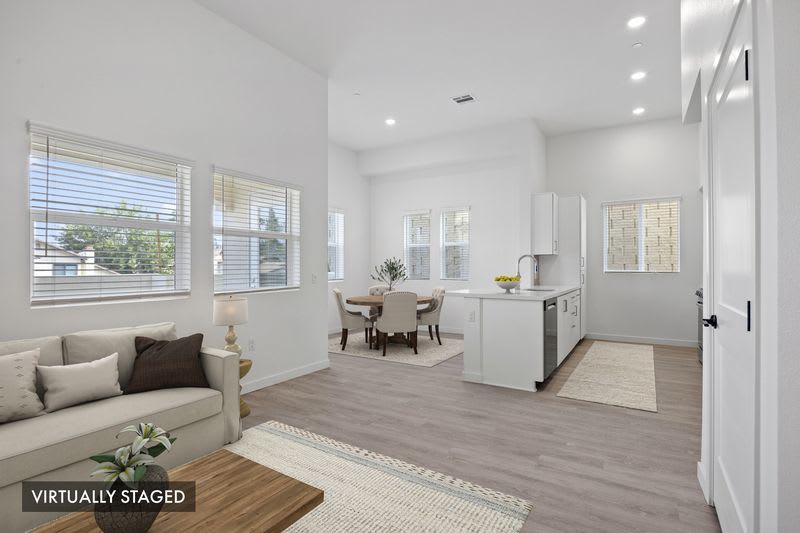 Open living and dining area with contemporary finishes, large windows, and adjacent kitchen at Canyon Bluffs Apartment Homes in Riverside, California