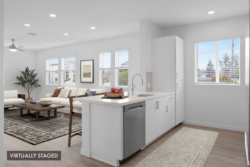 Bright kitchen and dining area with white cabinetry, center island, open floor plan, and modern finishes at Canyon Bluffs Apartment Homes in Riverside, California