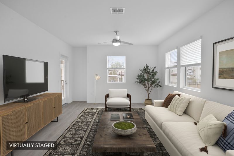 Open-concept living room with modern seating, large area rug, ceiling fan, and abundant natural light at Canyon Bluffs Apartment Homes in Riverside, California