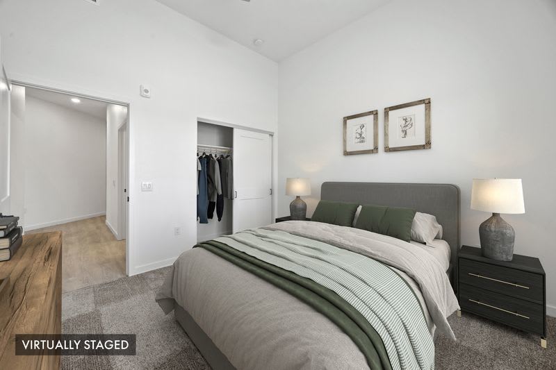 Bedroom with plush carpeting, sliding-door closet, modern furnishings, and natural light at Canyon Bluffs Apartment Homes in Riverside, California