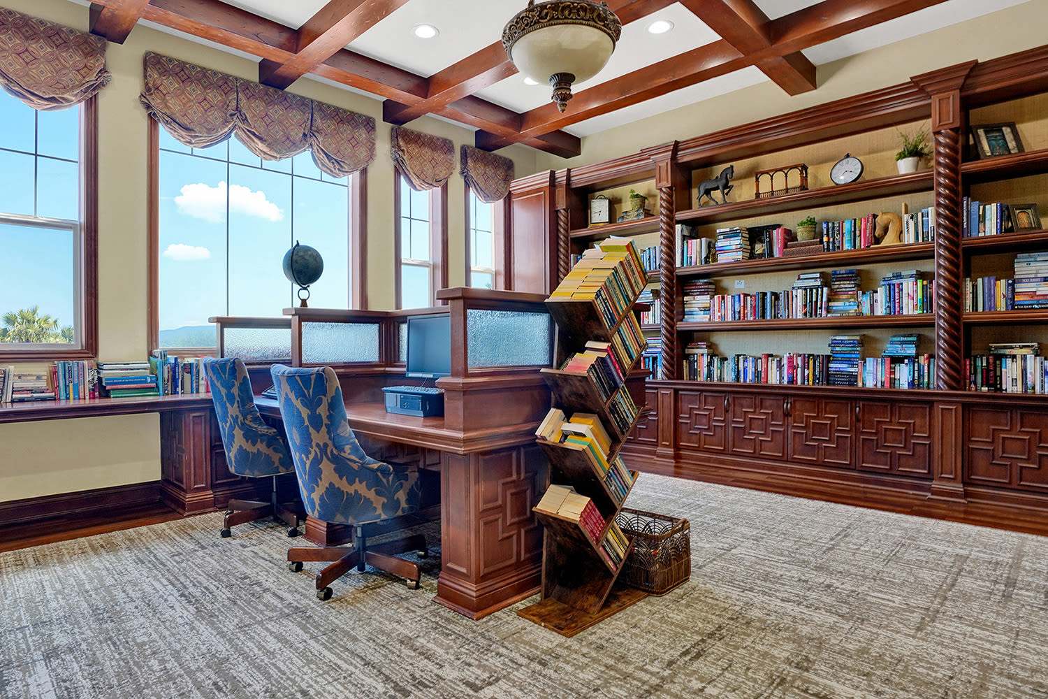 Senior living library with bookshelves, study desks, and large windows at Estancia Del Sol in Corona, California