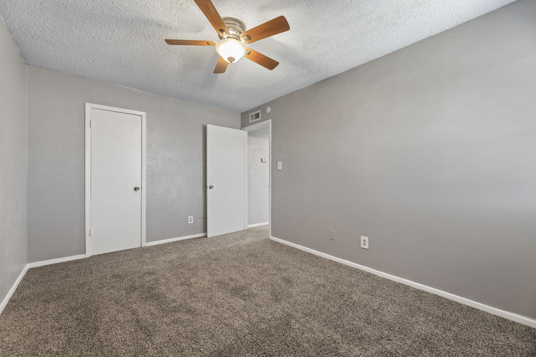 Bedroom with ceiling fan and window at Saddle Ridge Apartments in Weatherford, Texas