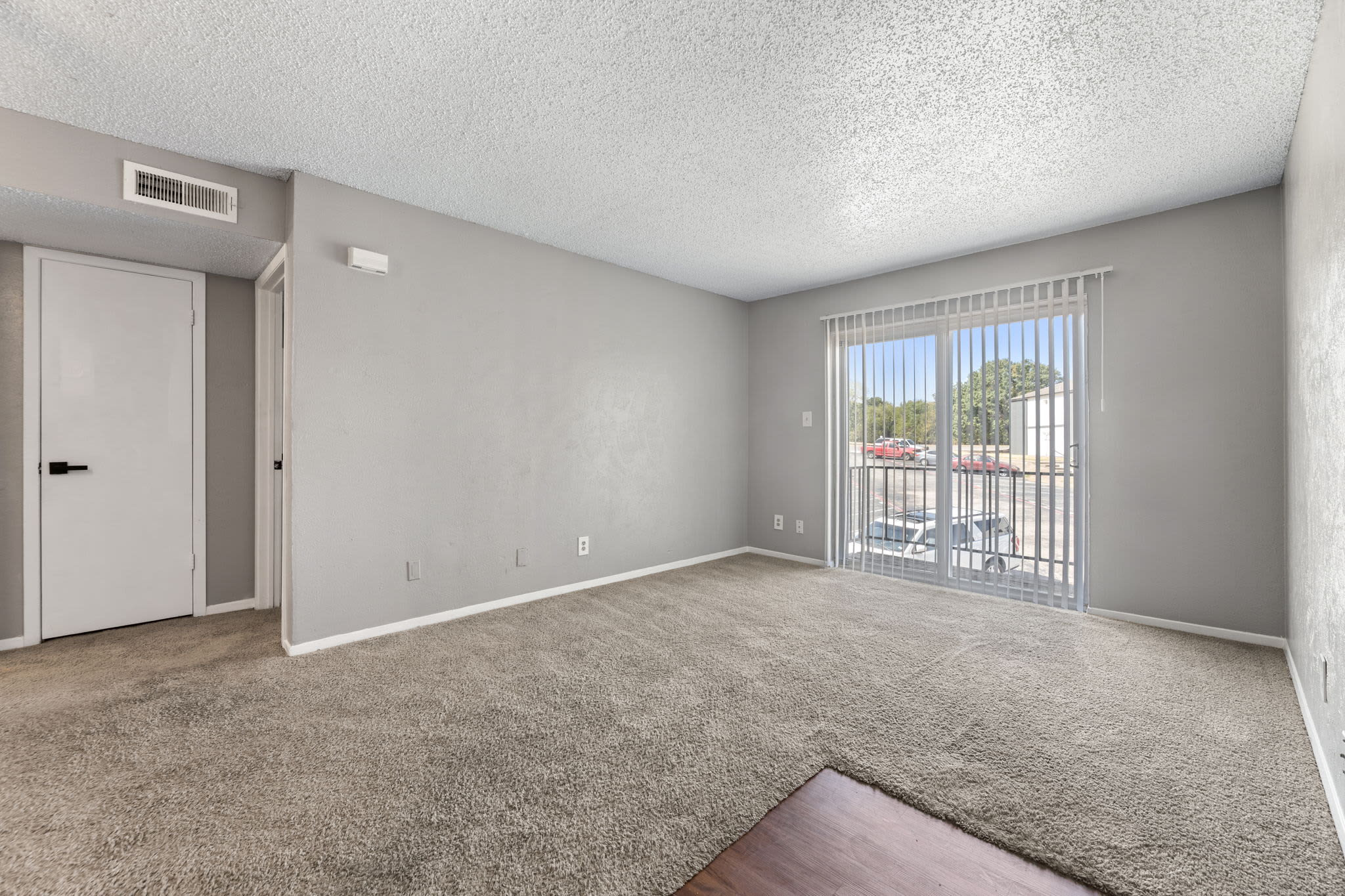 Living area with sliding glass door and parking view at Saddle Ridge Apartments in Weatherford, Texas