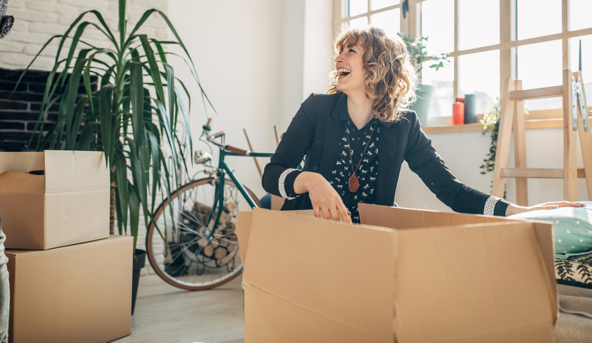 A woman packs belongings into a cardboard box for Our Self Storage.