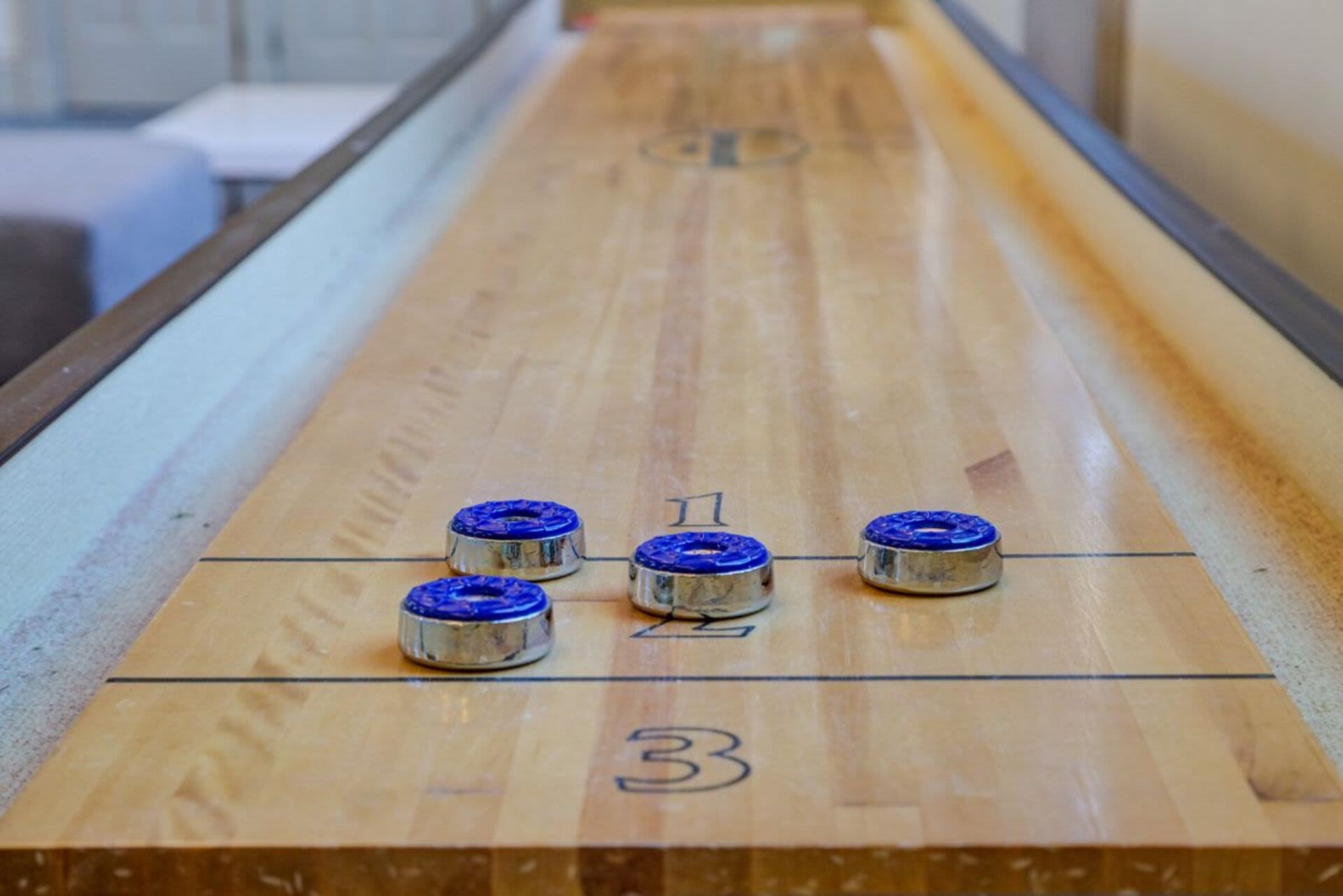 Shuffleboard table with three blue pucks at Bethany Apartments in Hanover, Massachusetts