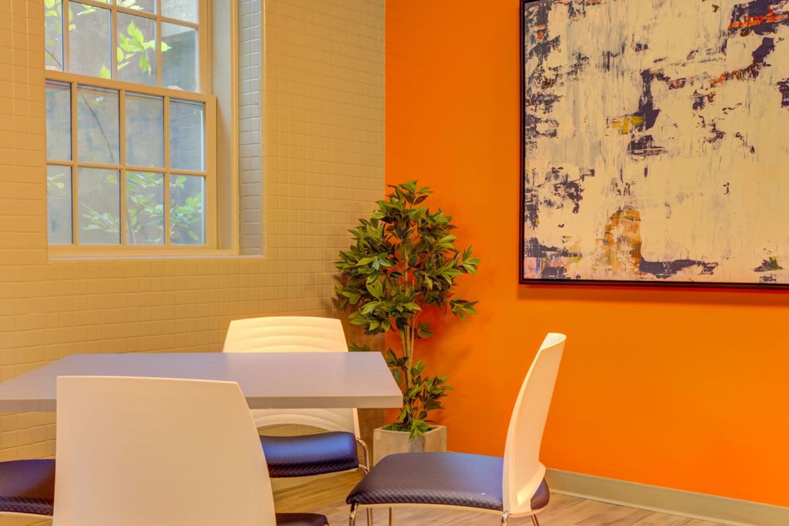 Table with chairs and a plant in a community room at Bethany Apartments in Hanover, Massachusetts