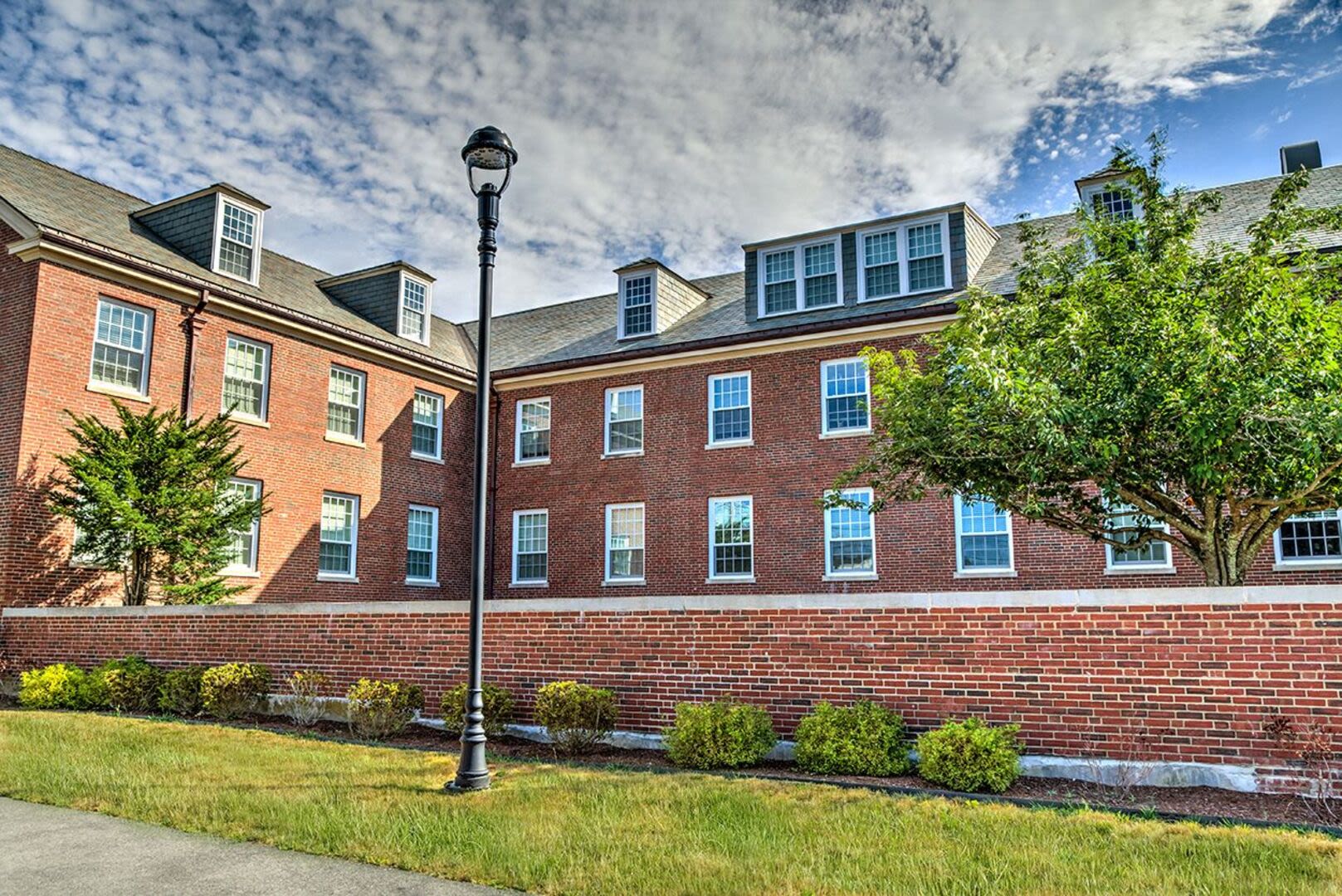 External view of an apartment with large trees at Bethany Apartments in Hanover, Massachusetts