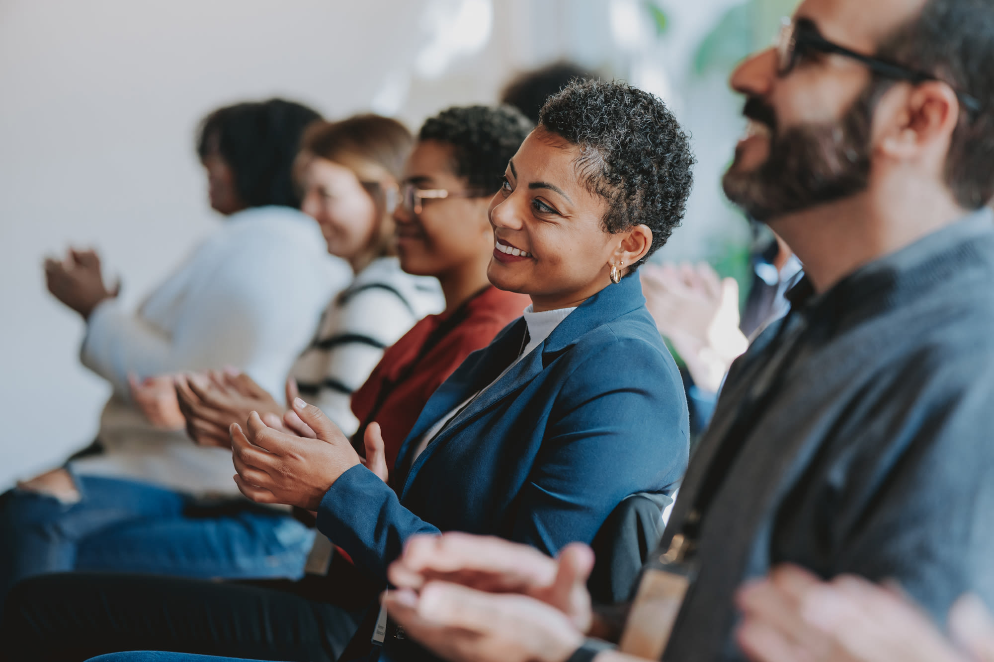 Image of diverse people clapping at a meeting.