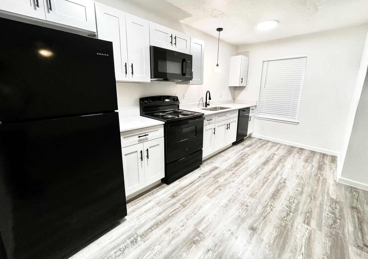 Fully equipped kitchen with granite countertops stainless steel appliances like a refrigerator, stove, and drawer microwave at Grapeland Apartments in Grapeland, Texas