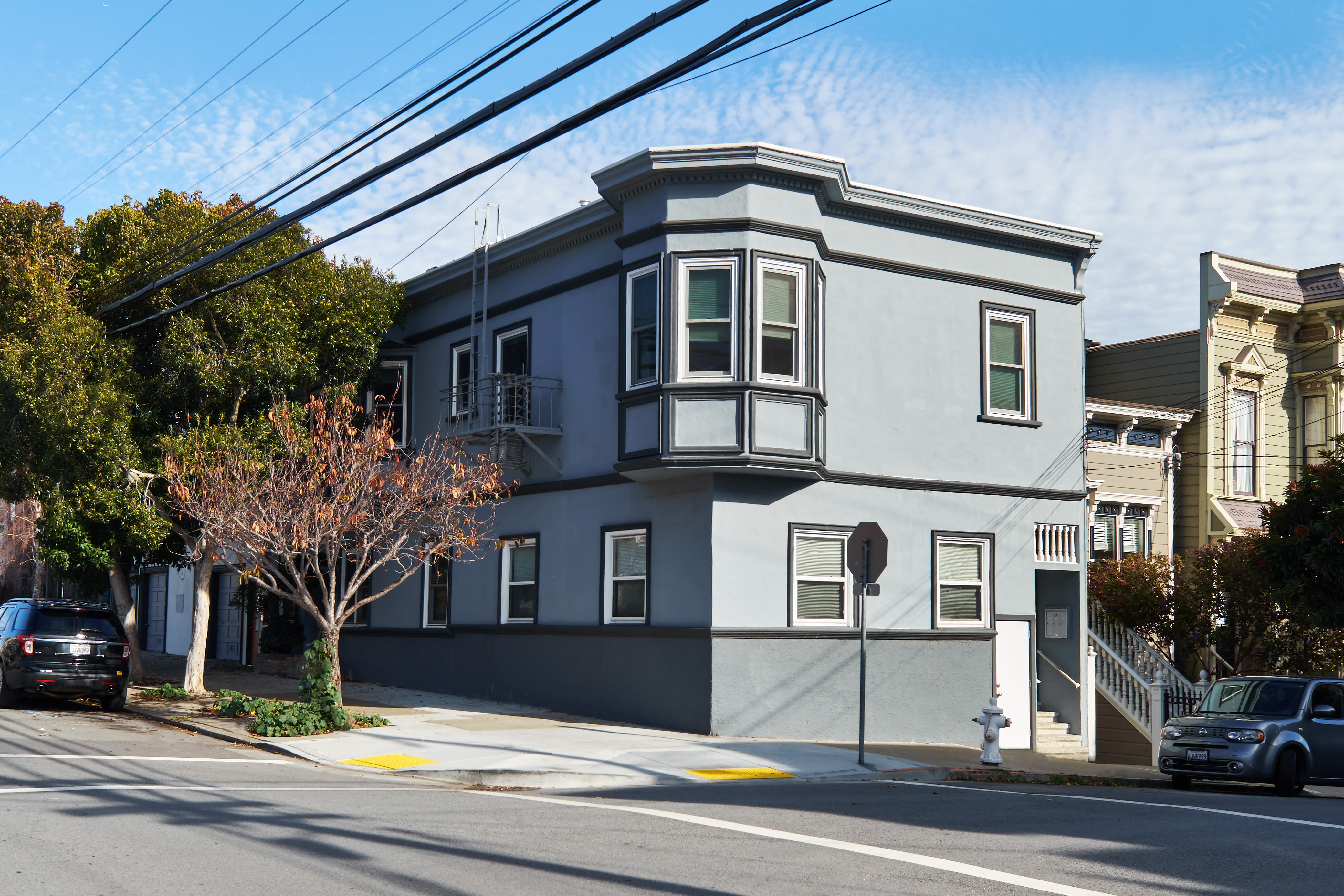 Two-story gray corner building with bay window