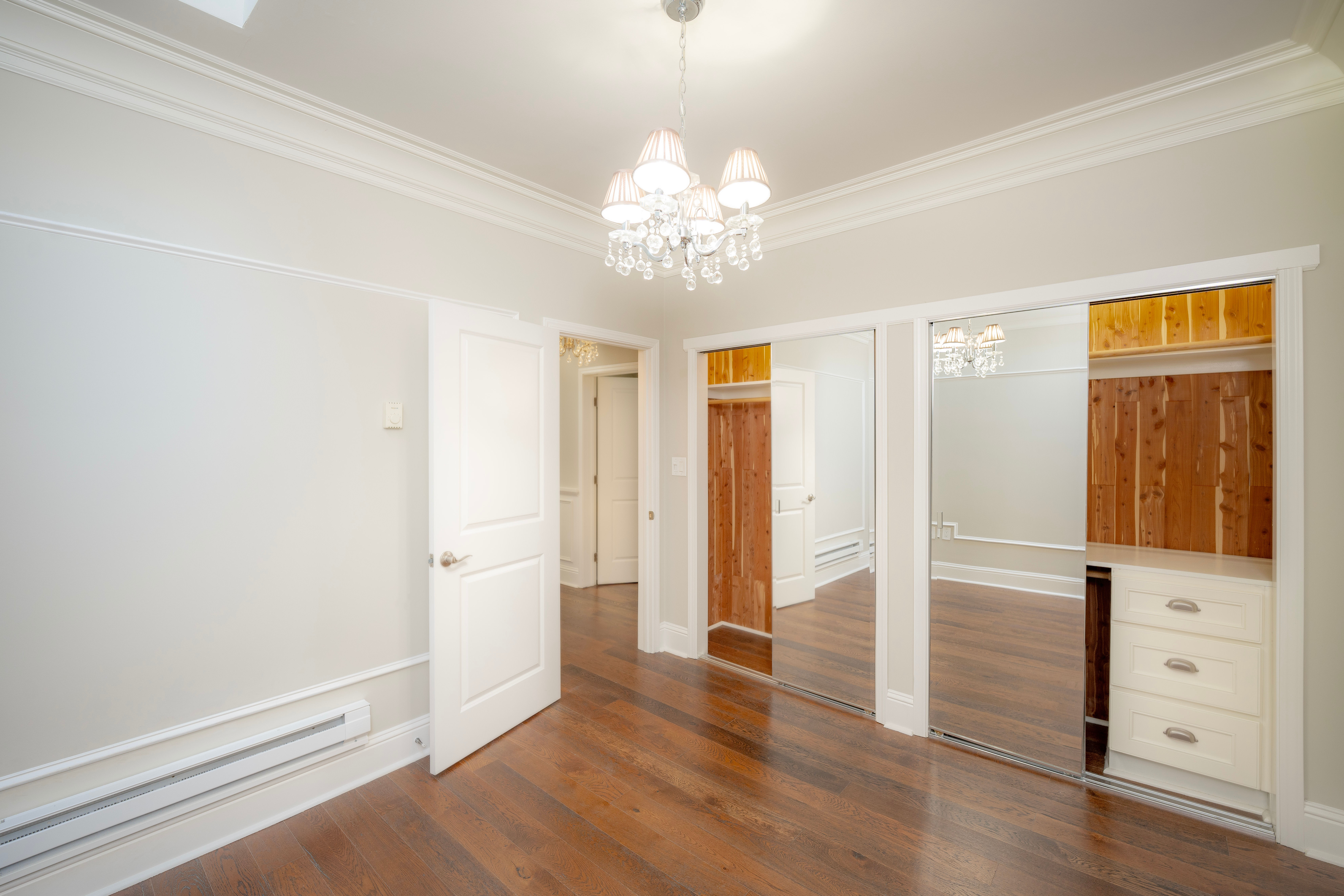 Empty room with chandelier and mirrored closet