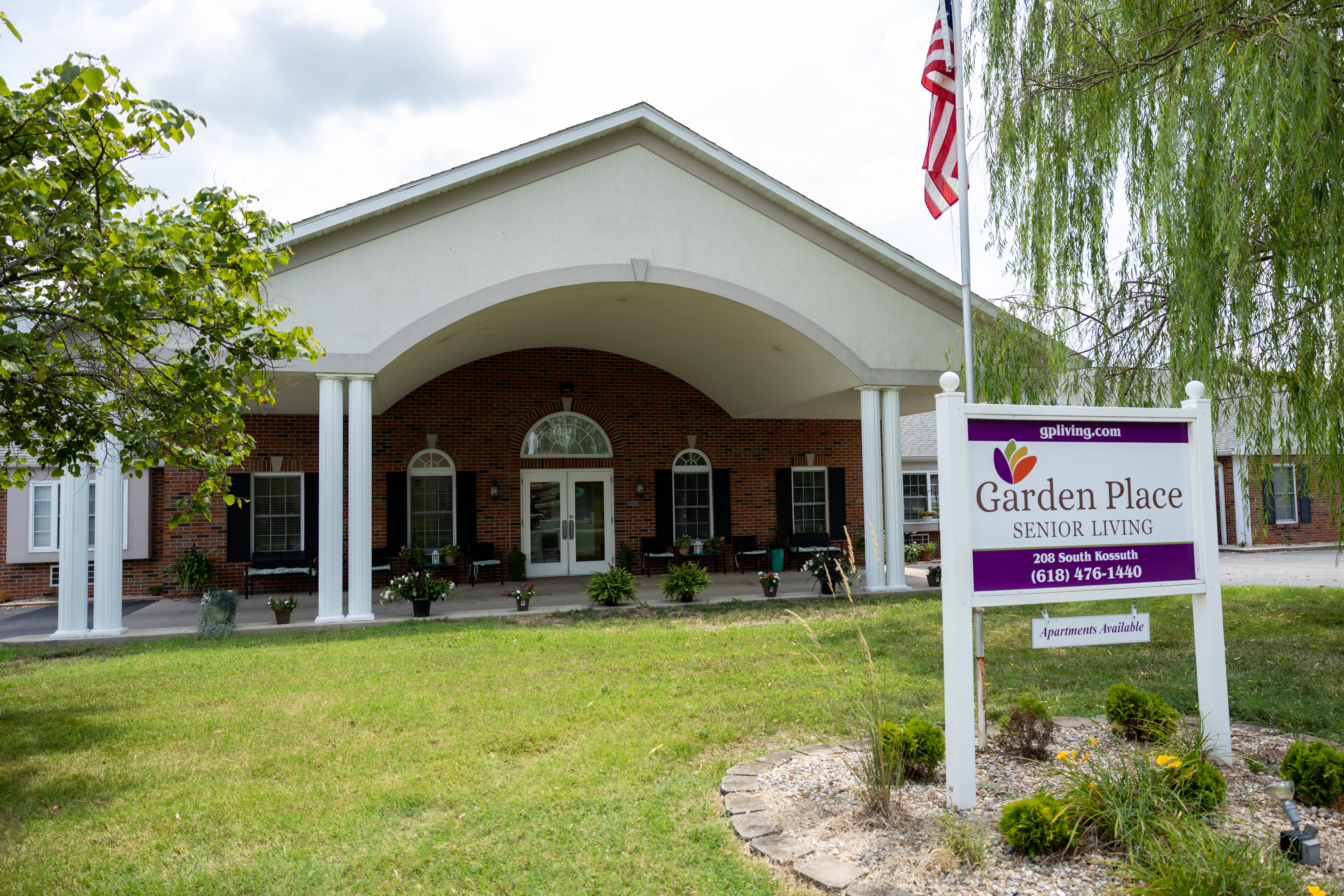 Entrance of Garden Place Senior Living with sign and American flag at Garden Place Millstadt in Millstadt, Illinois