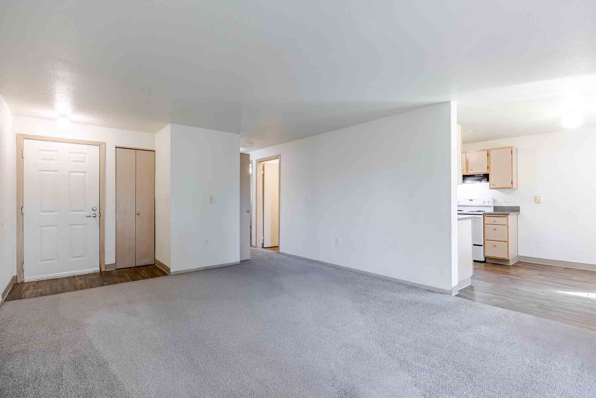 Empty living room with gray carpet and view of kitchen at Marketplace Apartments in Vancouver, Washington
