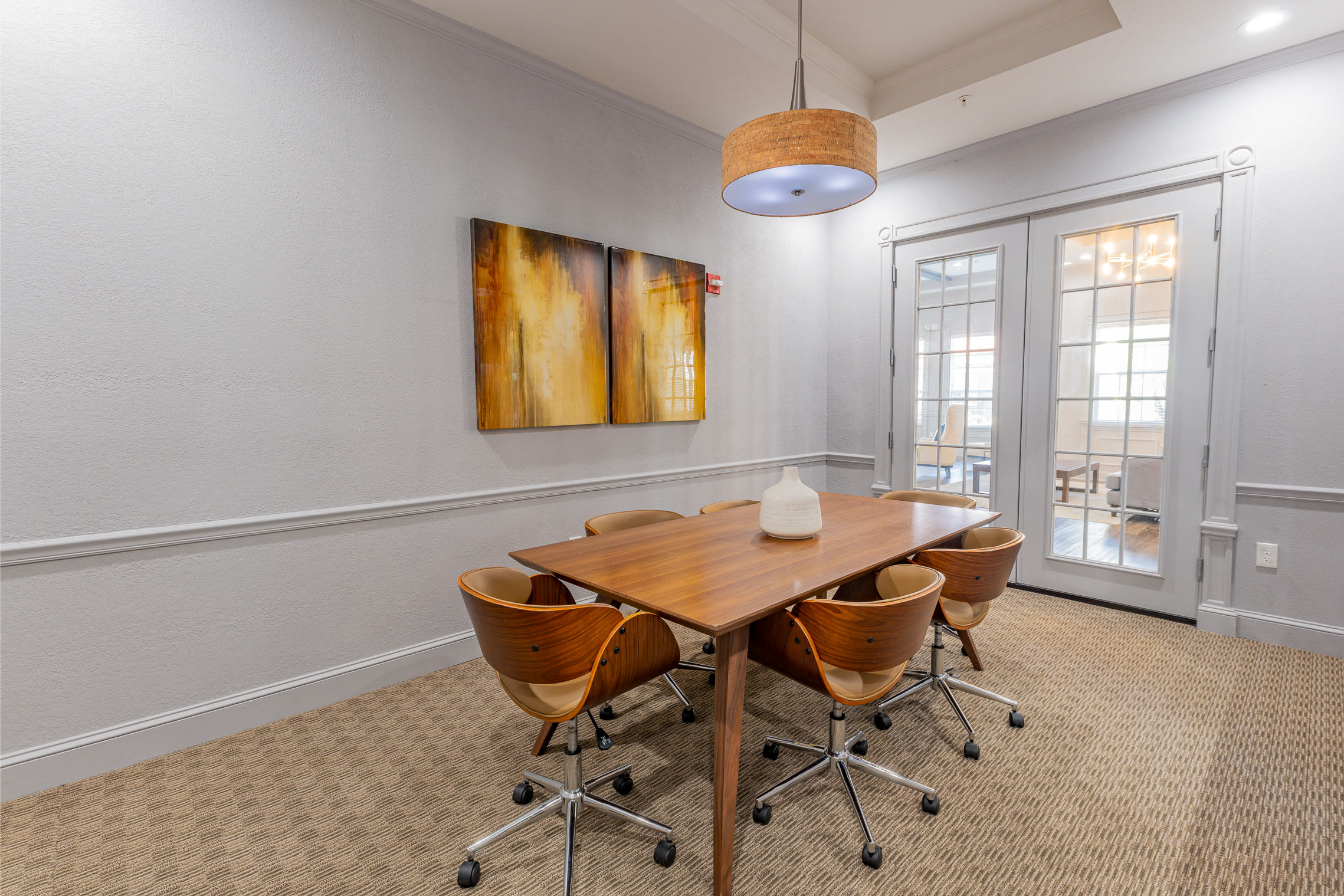 Modern meeting room with wooden table, chairs, and abstract wall art at Century Capital City in Tallahassee, Florida